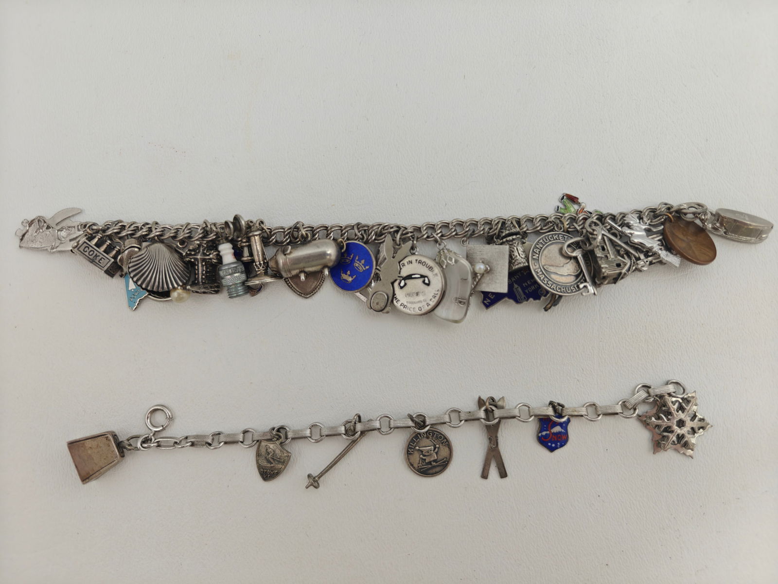 Two Vintage Sterling Charm Bracelets; 123g: Two Vintage Sterling Charm bracelets. One ski oriented with 7 charms, 6" long. One USA travel oriented with 31 charms, 6 1/2' long. Total weight 123g