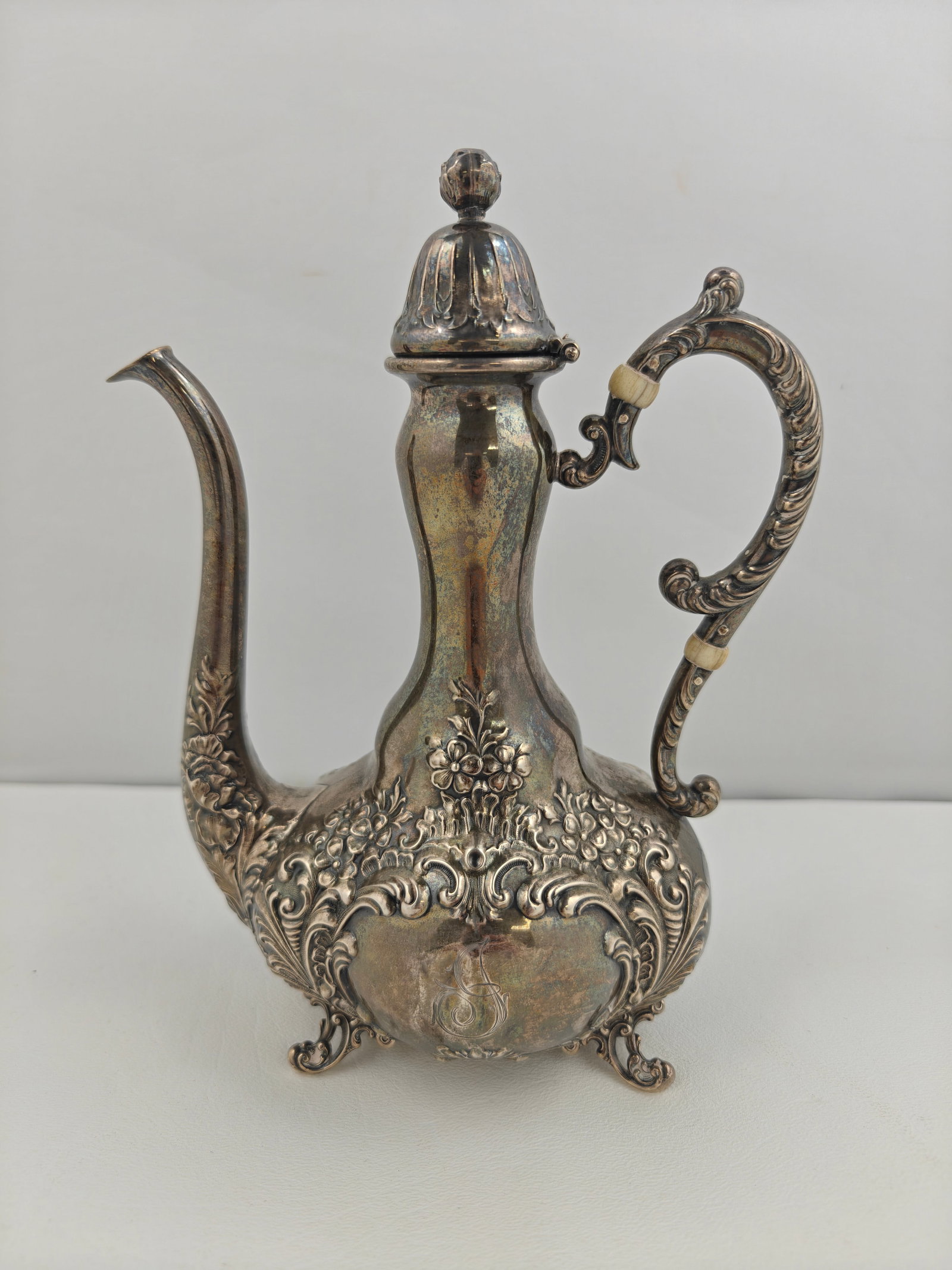 Victorian Style Sterling Coffee or Chocolate Pot, 247g: Ornate sterling coffee or chocolate pot, 8 inches tall, with repouss? floral and scroll decoration, domed lid, and scrolled handle. The bulbous body rests on four decorative feet and features a monogr