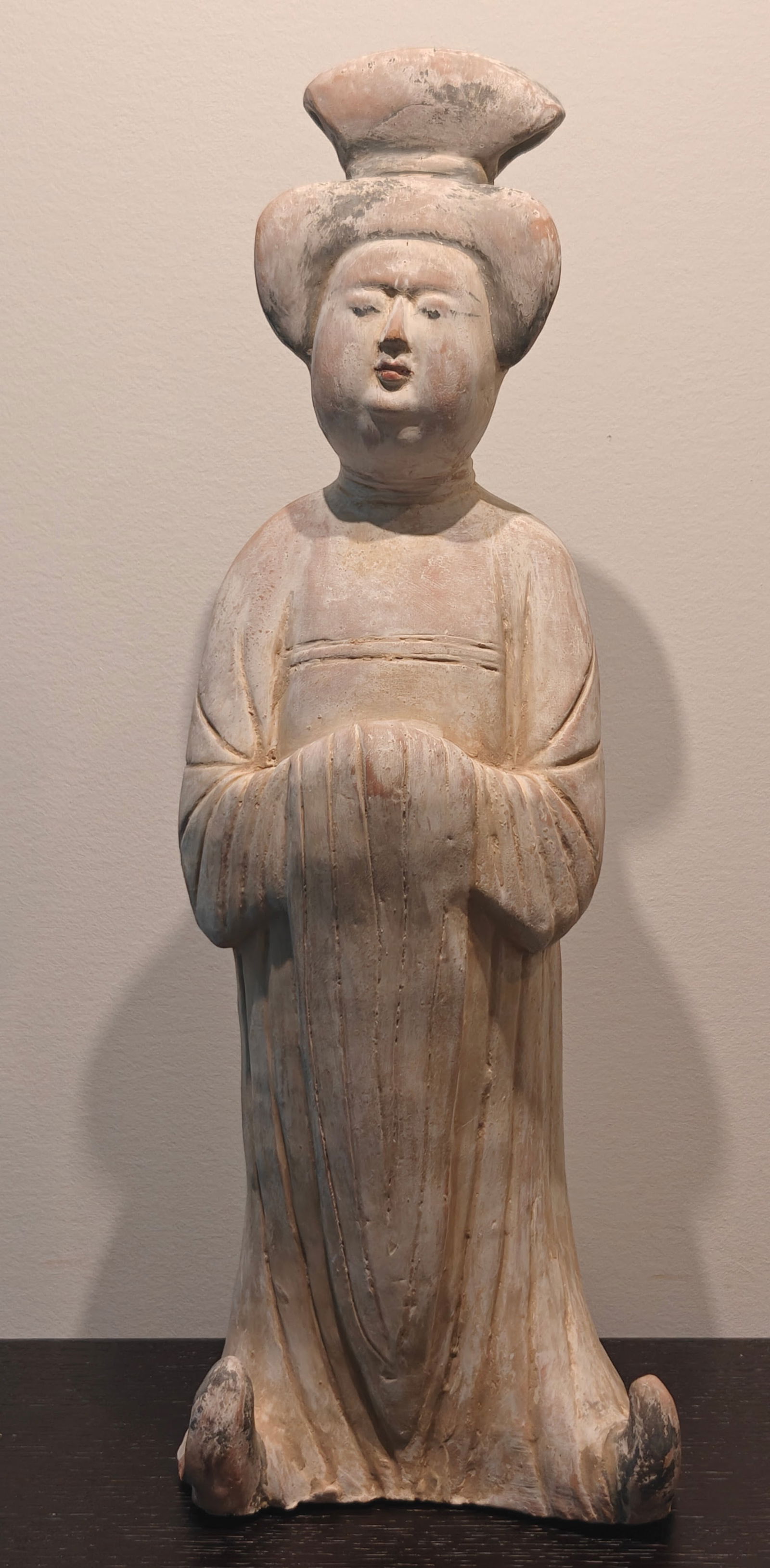 Chinese Terracotta Reproduction Tang Dynasty Court Lady Figurine, 18": Terracotta reproduction of a Tang Dynasty court lady, shown kneeling with hands folded and wearing a long flowing robe. The figure retains traces of original style polychrome pigments with a high topk