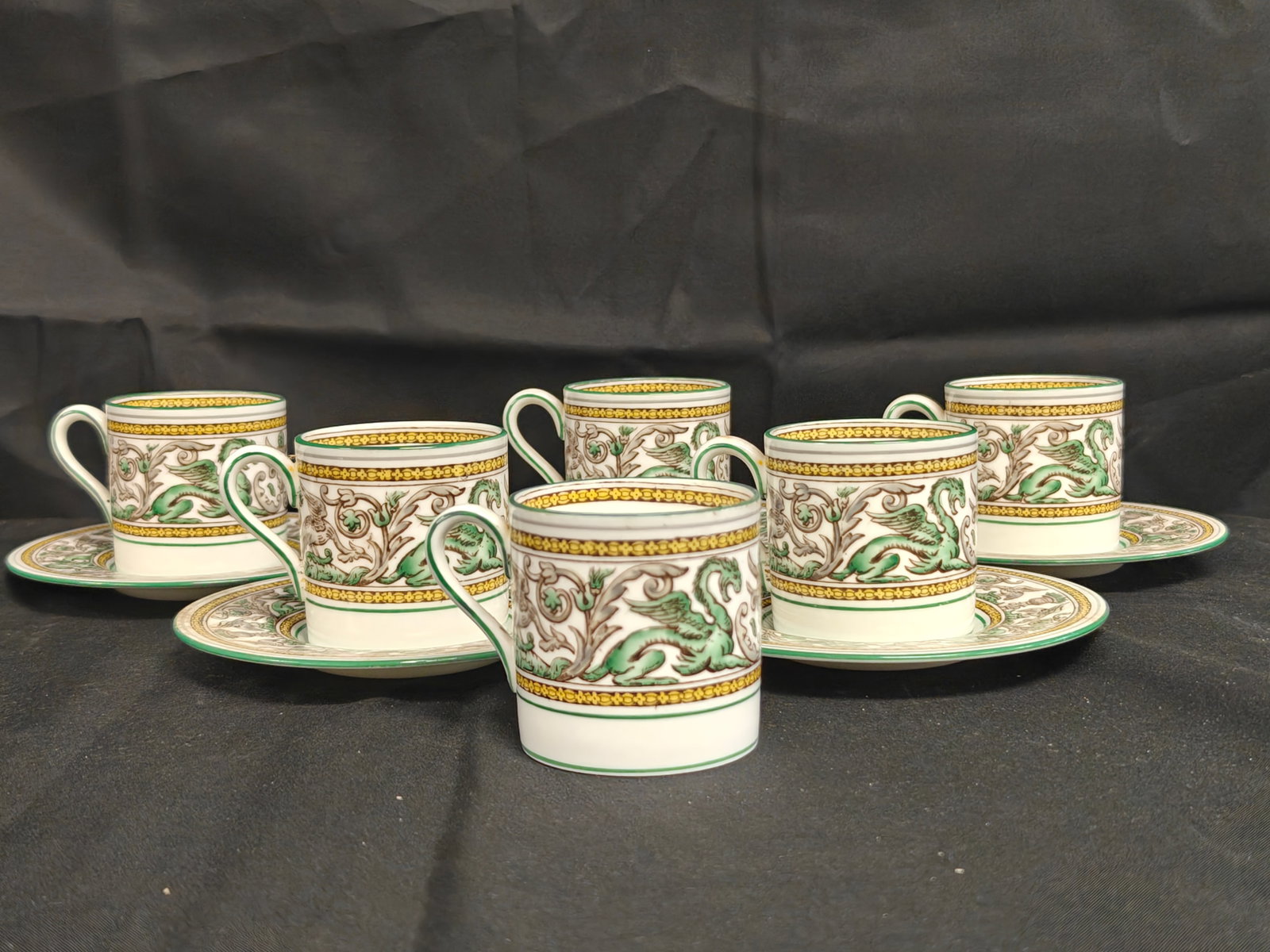 Set of 6 Wedgwood Florentine Green W3606 Demi-Tasse Cups and 5 Saucers: A group of Wedgwood bone china demi-tasse cups and saucers in the Florentine Green pattern, number W3606. The set includes six cups and five saucers, each decorated with the iconic Florentine border f