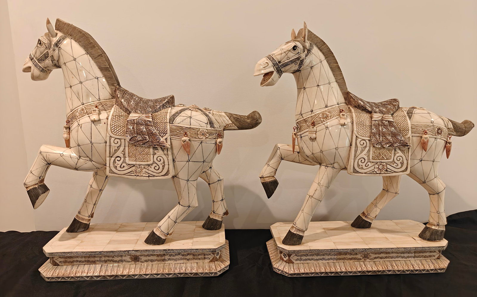 Pair of Large Tessellated Bone Tang-Style Horses: A pair of large decorative horses crafted in tessellated bone, inspired by Tang dynasty style. Each horse is finely detailed with geometric inlay, engraved floral and geometric patterns, and saddle de