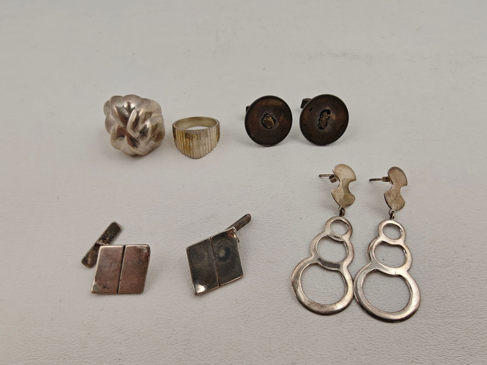 Sterling Jewelry Lot, 64g: A stylish collection of vintage and modern sterling jewelry weighing a total of 64 grams. The lot includes two bold sterling rings — one with a sculptural, organic form and the other with a ridged g
