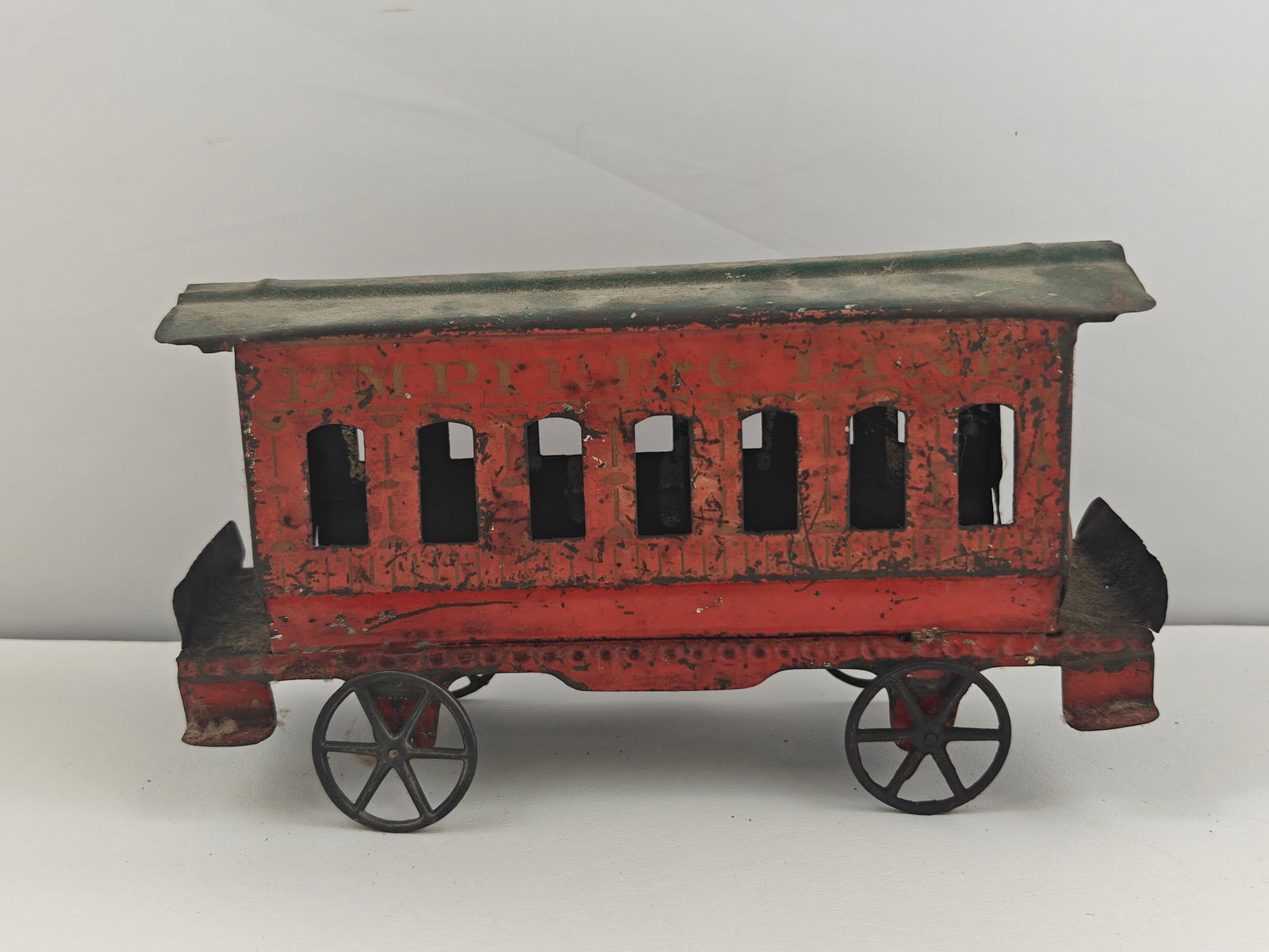 Antique Tin Toy Trolley Car: This antique tin toy trolley car, dating back to the late 19th century, showcases an early lithographed red finish with arched windows and hand-stenciled lettering that reads "Empire Line." The car re