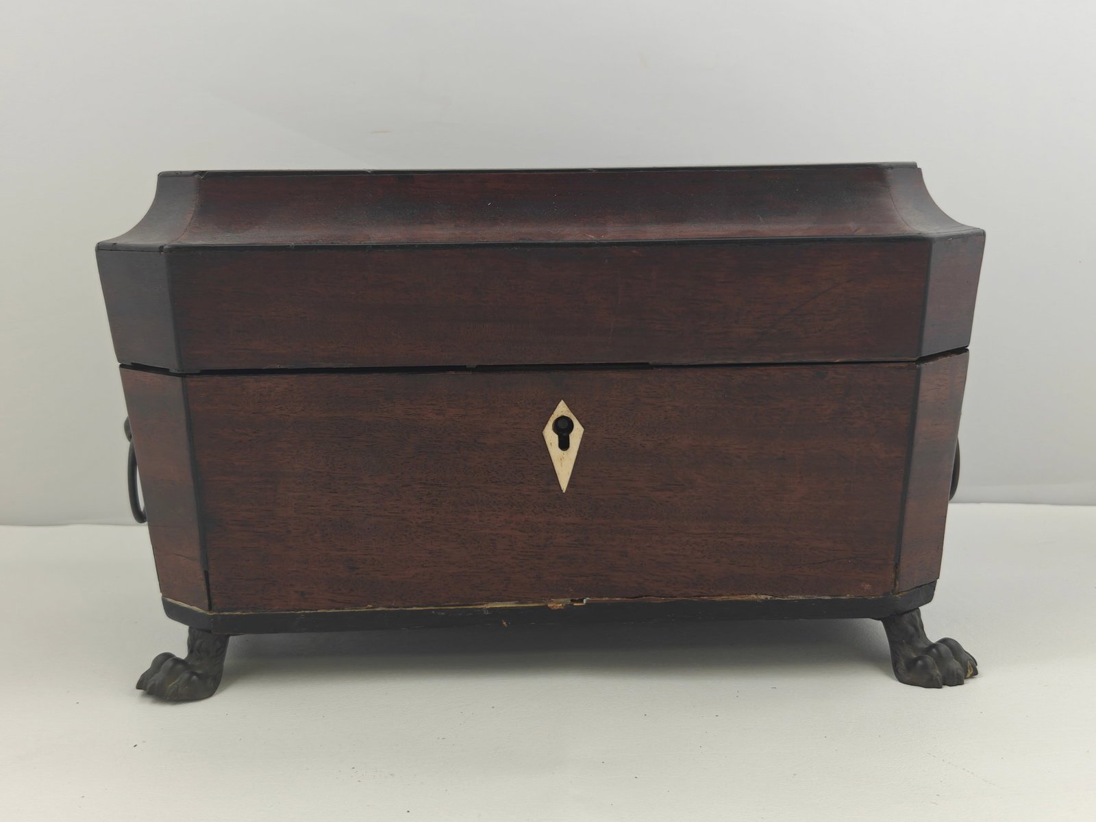 Georgian Mahogany English Lion Foot Tea Caddy: Handsome Georgian English tea caddy crafted in rich mahogany, raised on bold cast lion paw feet with decorative lion mask handles. The interior shows age and use with worn lining, but retains its orig