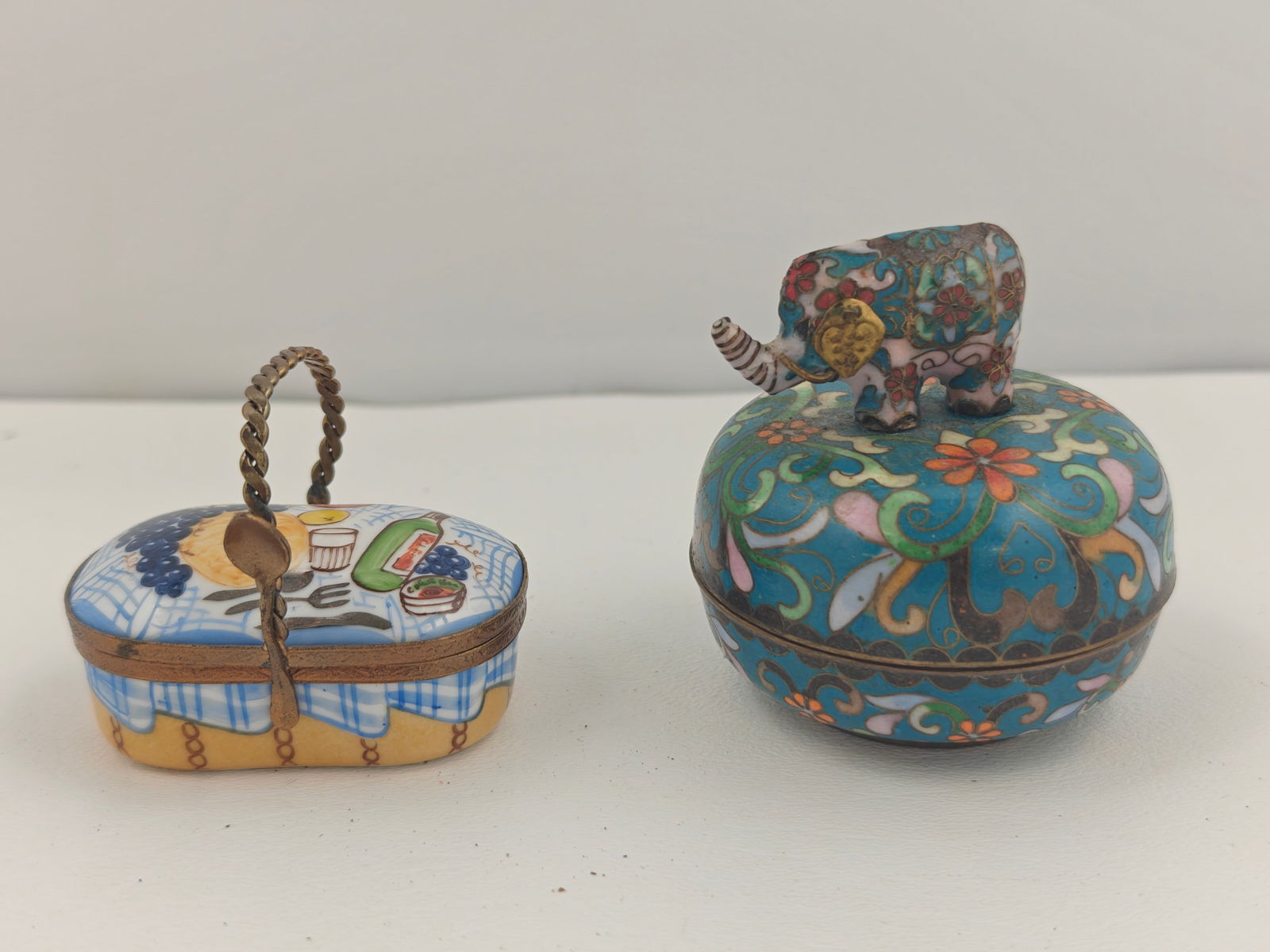 Ardleigh Elliott Music Box and Limoges Trinket Box: Pair of decorative boxes including a hand-painted Limoges porcelain trinket box featuring a picnic scene with grapes, wine, and fruit on a checkered tablecloth, marked “Limoges France Peint Main.&rd
