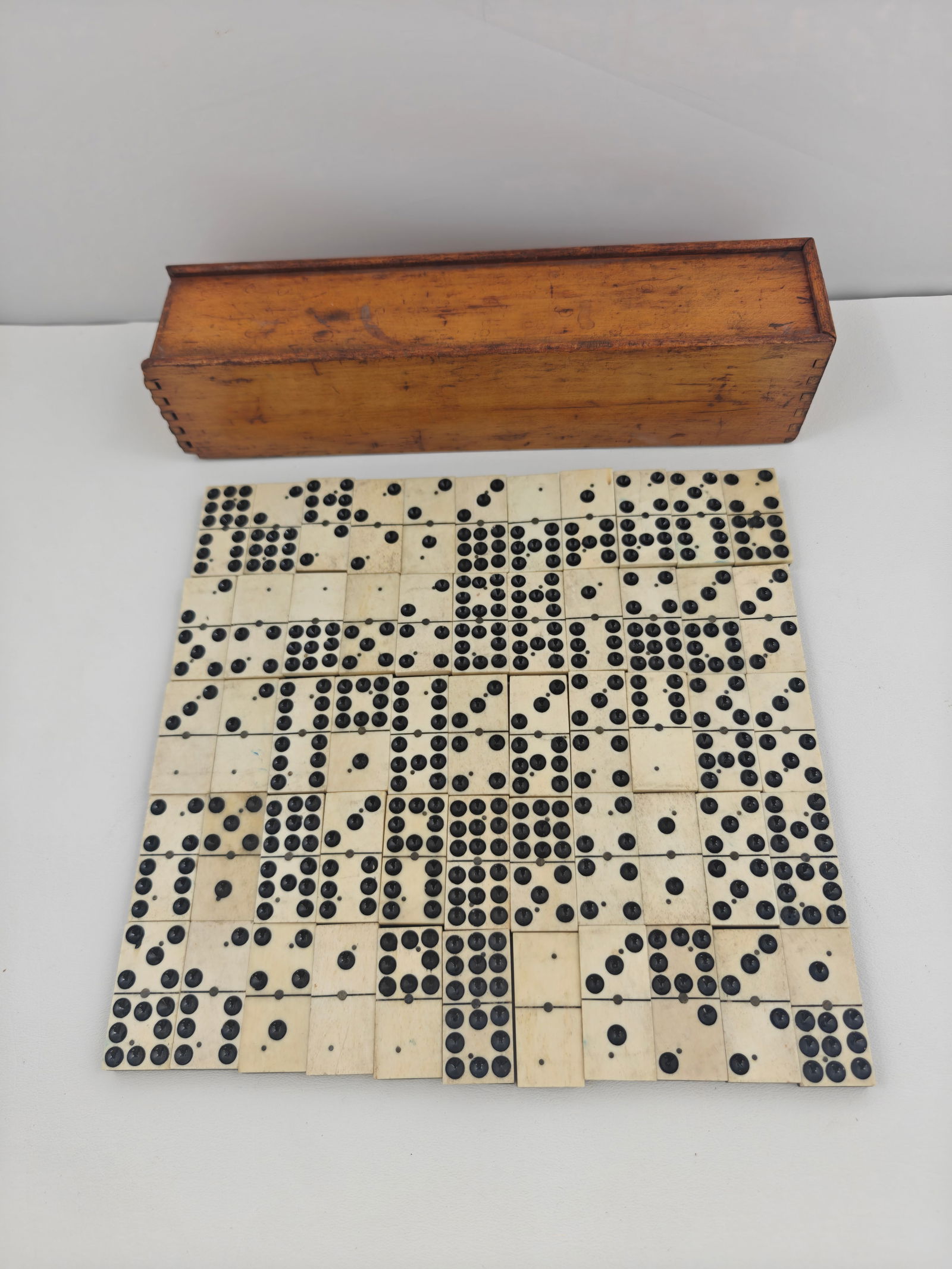 Antique Bone & Ebony Dominoes in Wooden Slide-Top Box: A 19th century domino set comprised of hand-carved bone tiles with ebony backs, housed in the original dovetail-joined wooden slide-top box. Complete with a full double-nine set of 55 tiles, each with