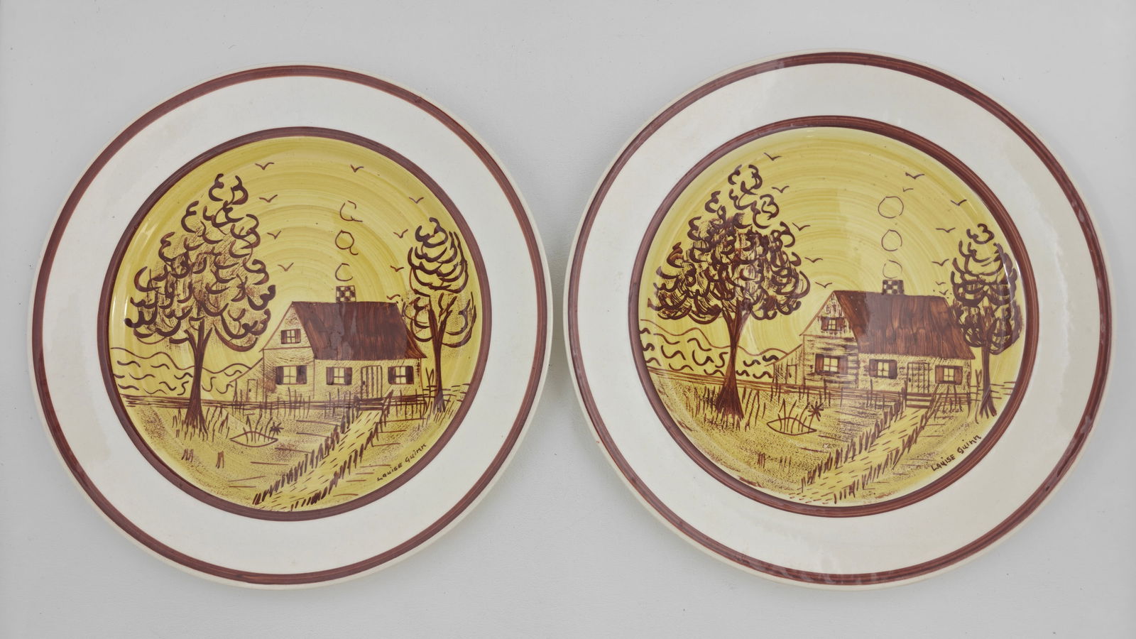 Pair of Blue Ridge Hand Painted Dinner Plates ? Cottage Scene by Louise Guinn: A charming pair of hand-painted Blue Ridge Southern Potteries dinner plates, each signed by artist Louise Guinn and numbered 6011. These plates feature a rustic cottage scene with trees, birds, and a