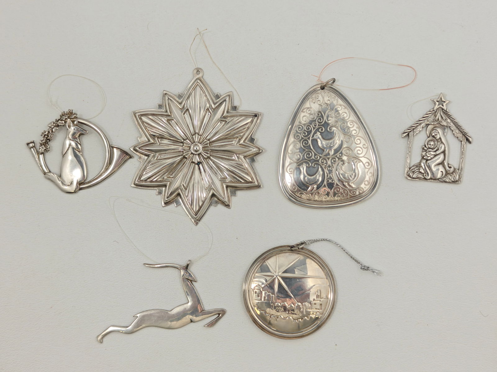 Six Assorted Sterling Christmas Ornaments: An elegant group of six sterling silver Christmas ornaments by Towle, Gorham, Reed and Barton, and others, including hand-hammered examples. Designs feature a radiant star, reindeer, nativity scene, f