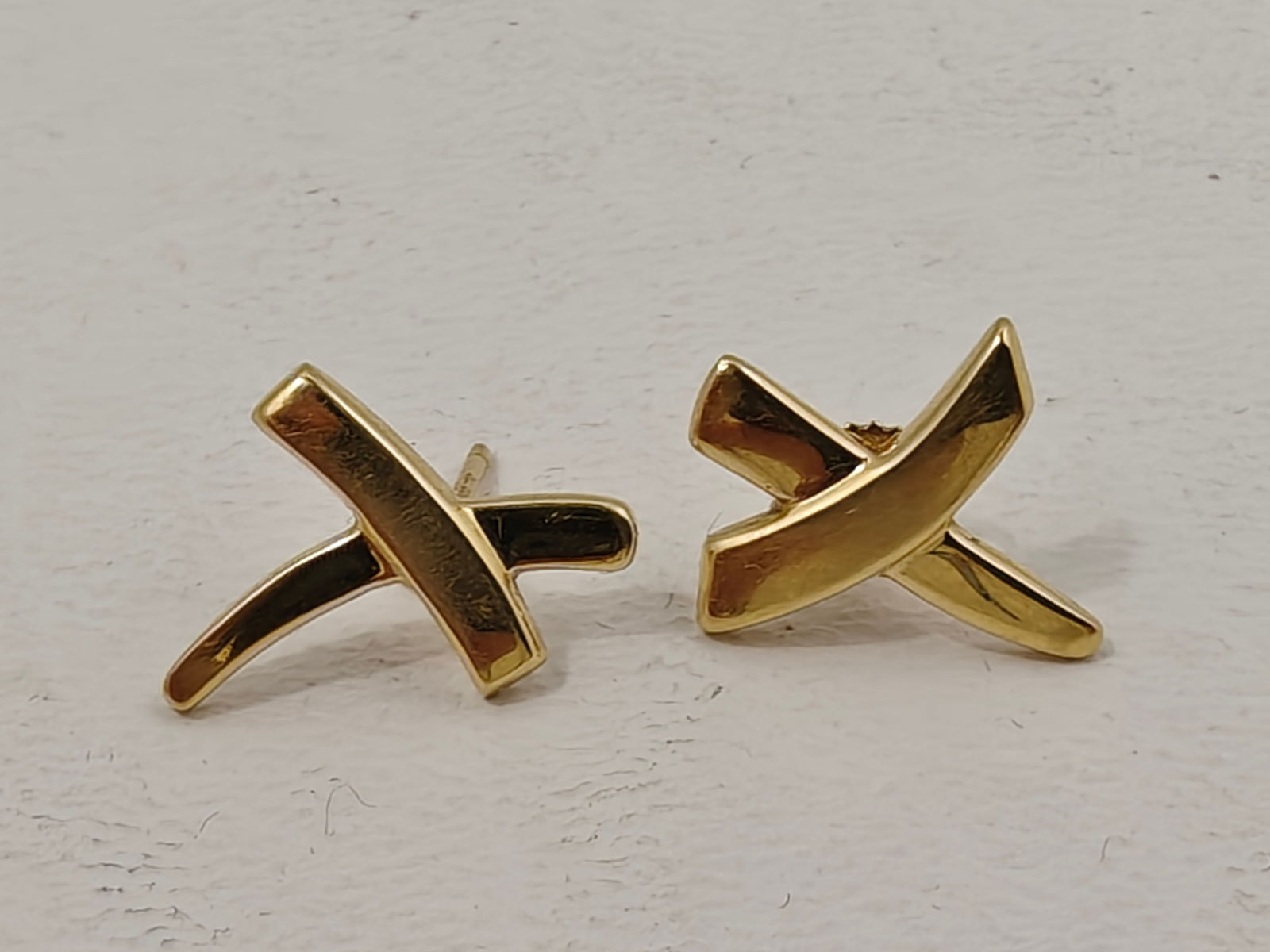 Tiffany & Co. 18K Gold Paloma Picasso Cross Earrings: Elegant Tiffany & Co. Paloma Picasso cross earrings crafted in 18K yellow gold and marked "750," "Tiffany & Co.," and "Paloma Picasso." Each earring features the designer's signature bold, sculptural