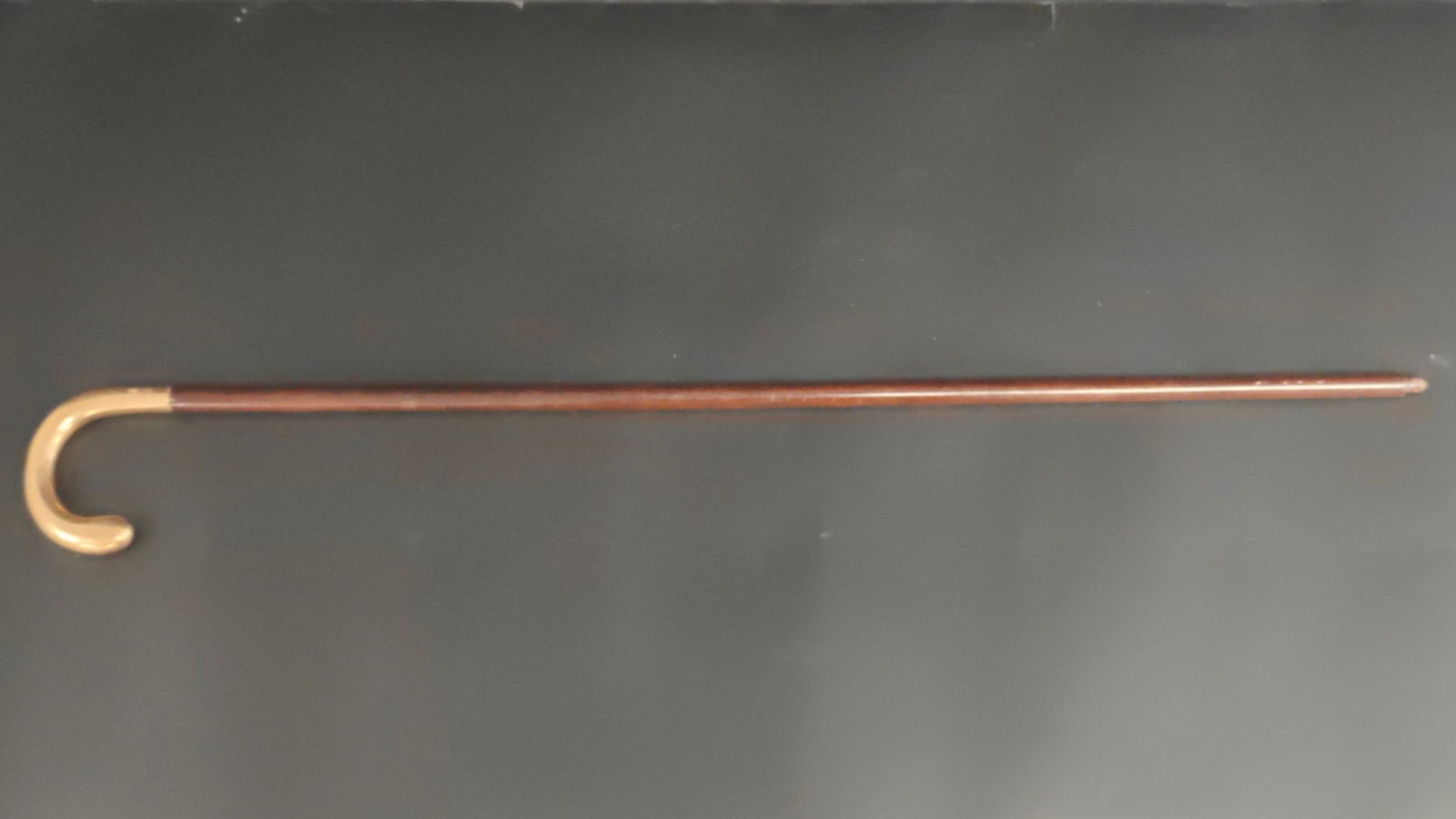 Antique Gentleman’s Cane with 14K Gold Handle: Early 20th century gentleman’s walking cane featuring a curved solid gold handle marked 14K. The handle is smoothly finished with visible age wear and patina, attached to a wooden shaft with a metal