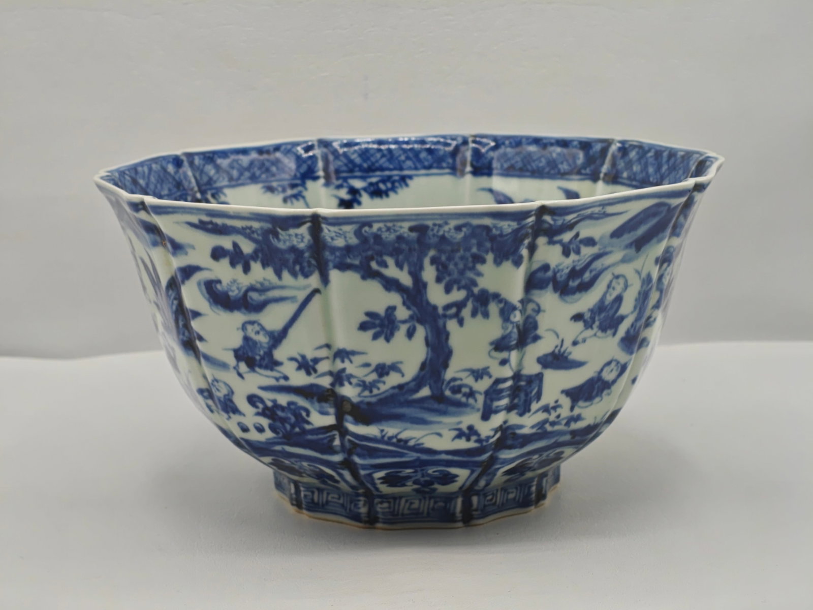 Chinese Blue and White Porcelain Scalloped Bowl with Figural Scene 9.5 Inches: Chinese blue and white porcelain bowl with a lobed scalloped form and hand painted decoration. The exterior features figural scenes of children at play in a garden setting with architectural and lands