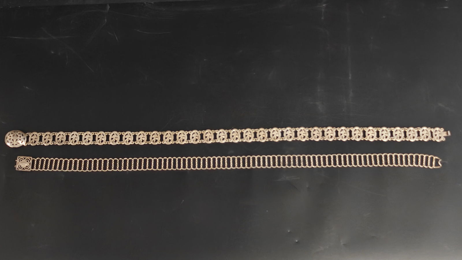 Straits Chinese Peranakan and Thai style linked metal belts with figural panels: Pair of vintage Southeast Asian belts including a Straits Chinese Peranakan style belt with oval figural panels and a Thai style linked belt with geometric square clasp and looped chain design, both i