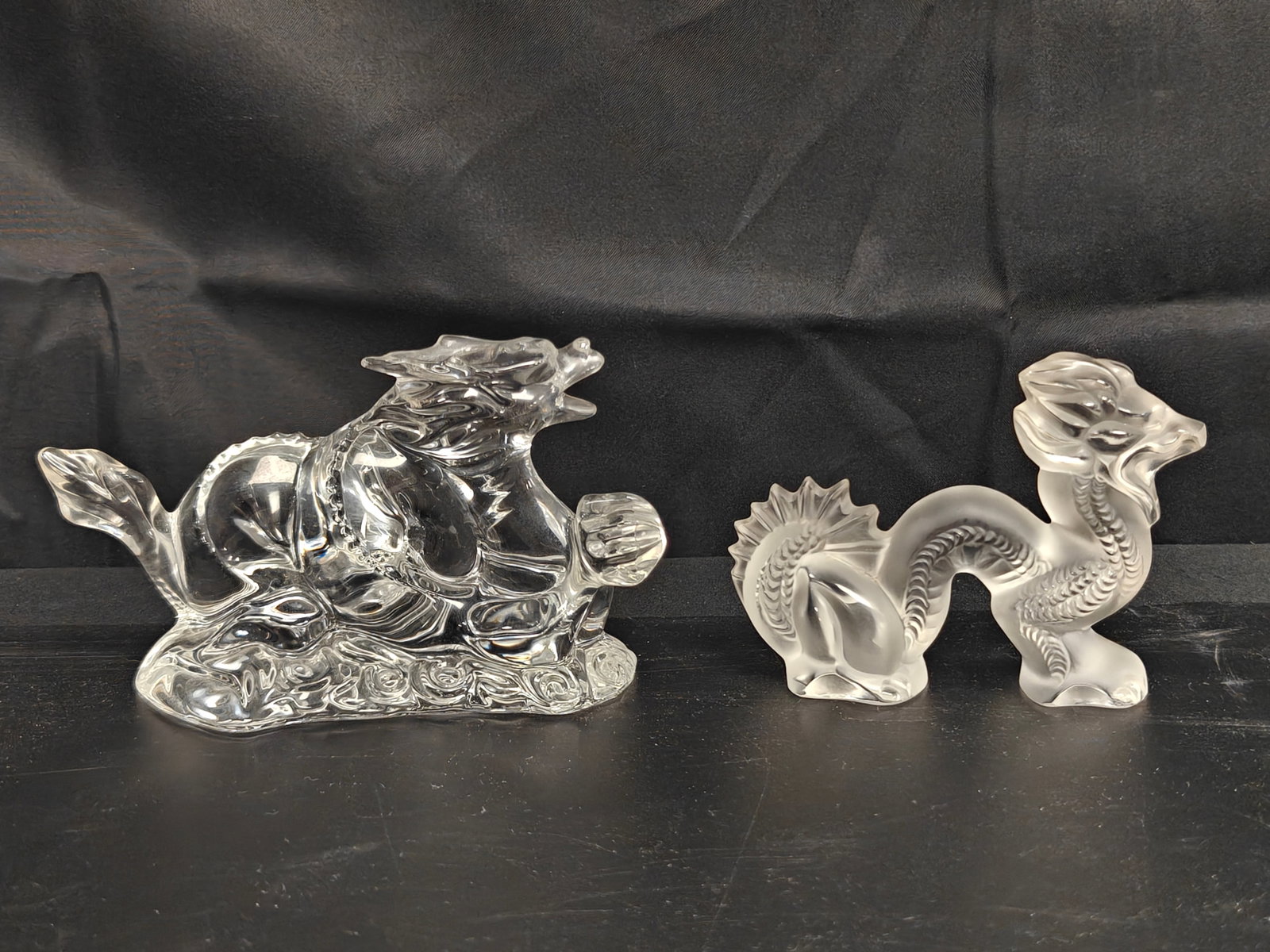 Baccarat & Lalique Crystal Dragon Figures, Pair: Pair of French crystal dragon figures including a clear Baccarat dragon with swirling cloud base and a frosted Lalique dragon with finely detailed scales and flowing mane. Both retain their respective