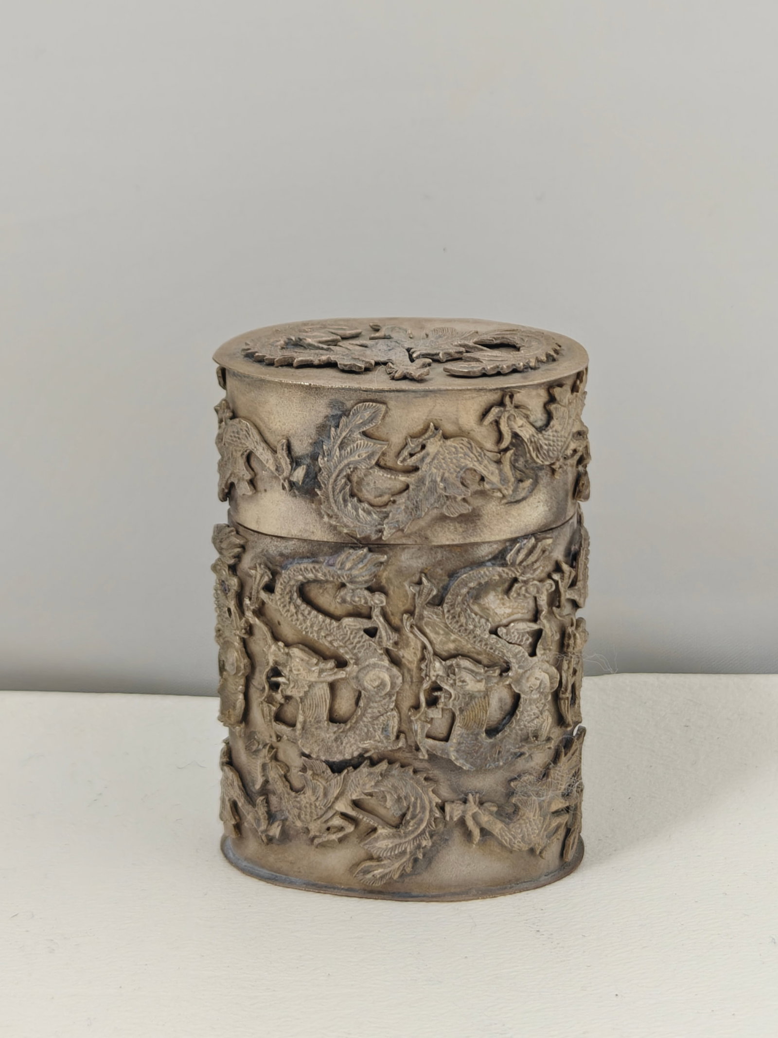 Chinese Dragon & Phoenix Pierced Metal Toothpick Box: Decorative cylindrical Chinese-style toothpick box featuring intricate openwork relief decoration with dragons and phoenixes encircling the body and lid. The removable lid is similarly decorated, and 