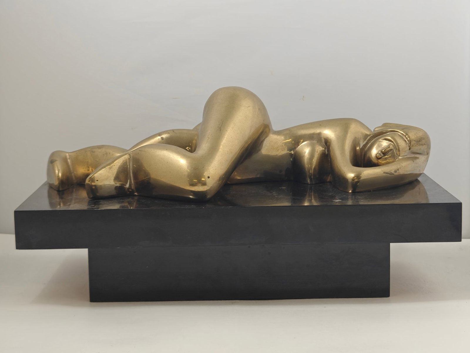William P. Katz Bronze Reclining Female Figure Sculpture: Polished bronze sculpture by William P. Katz depicting a stylized reclining female nude in a modernist form, mounted on a black rectangular plinth. Signed "WPK" on the right foot. Measures approximate