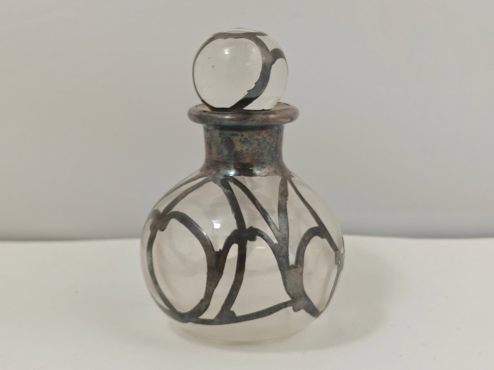 Art Nouveau Sterling Silver Overlay Glass Perfume Bottle: Art Nouveau clear glass perfume bottle featuring an elegant sterling silver overlay in a flowing organic design with matching silver-mounted neck and coordinating glass stopper. The bottle has a round