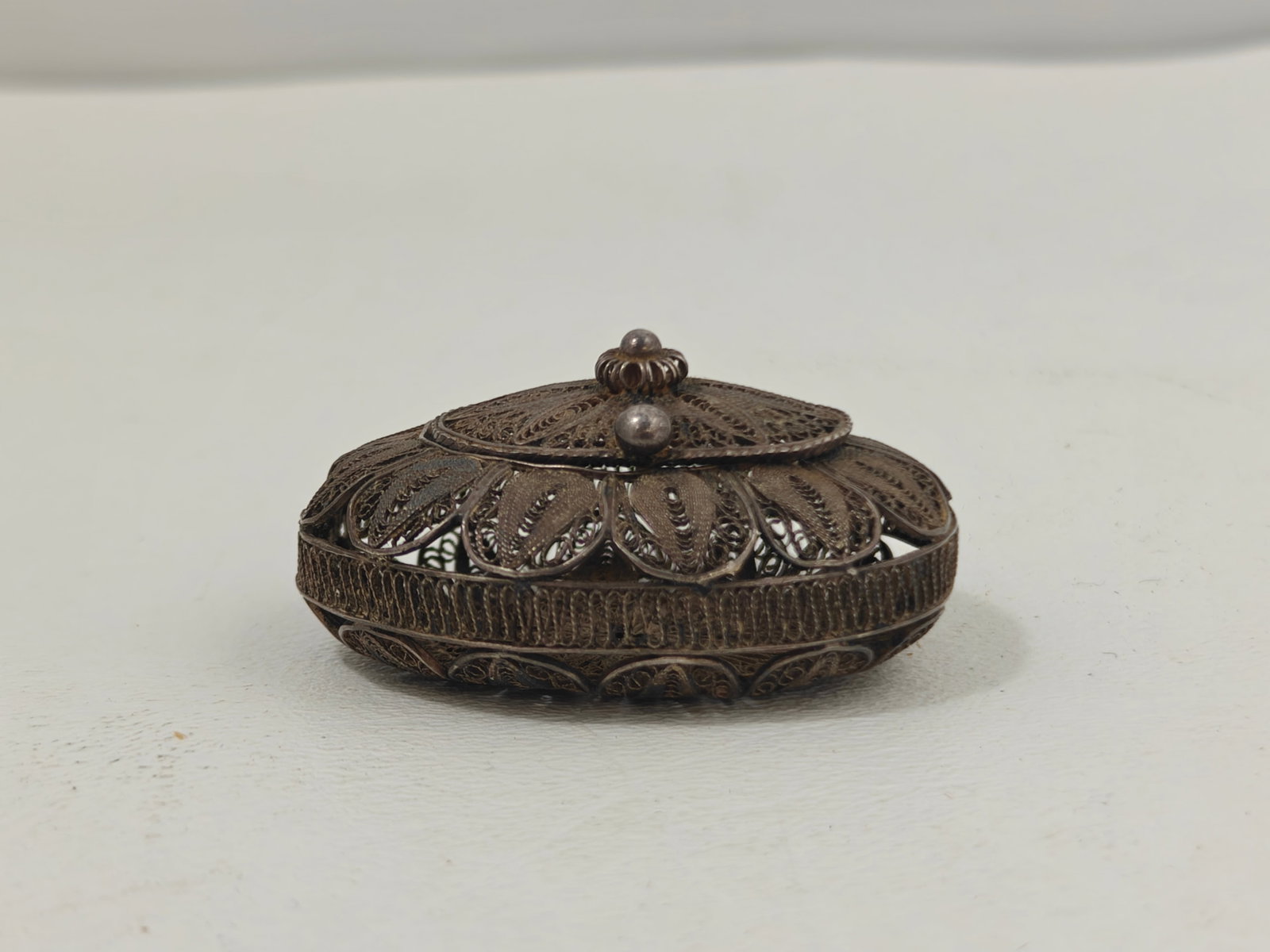 Vintage Sterling Silver Filigree Pill Box: Delicate vintage sterling silver filigree pill box of oval form featuring intricate hand-worked openwork floral and scroll decoration throughout. The hinged lid opens to reveal a small interior compar