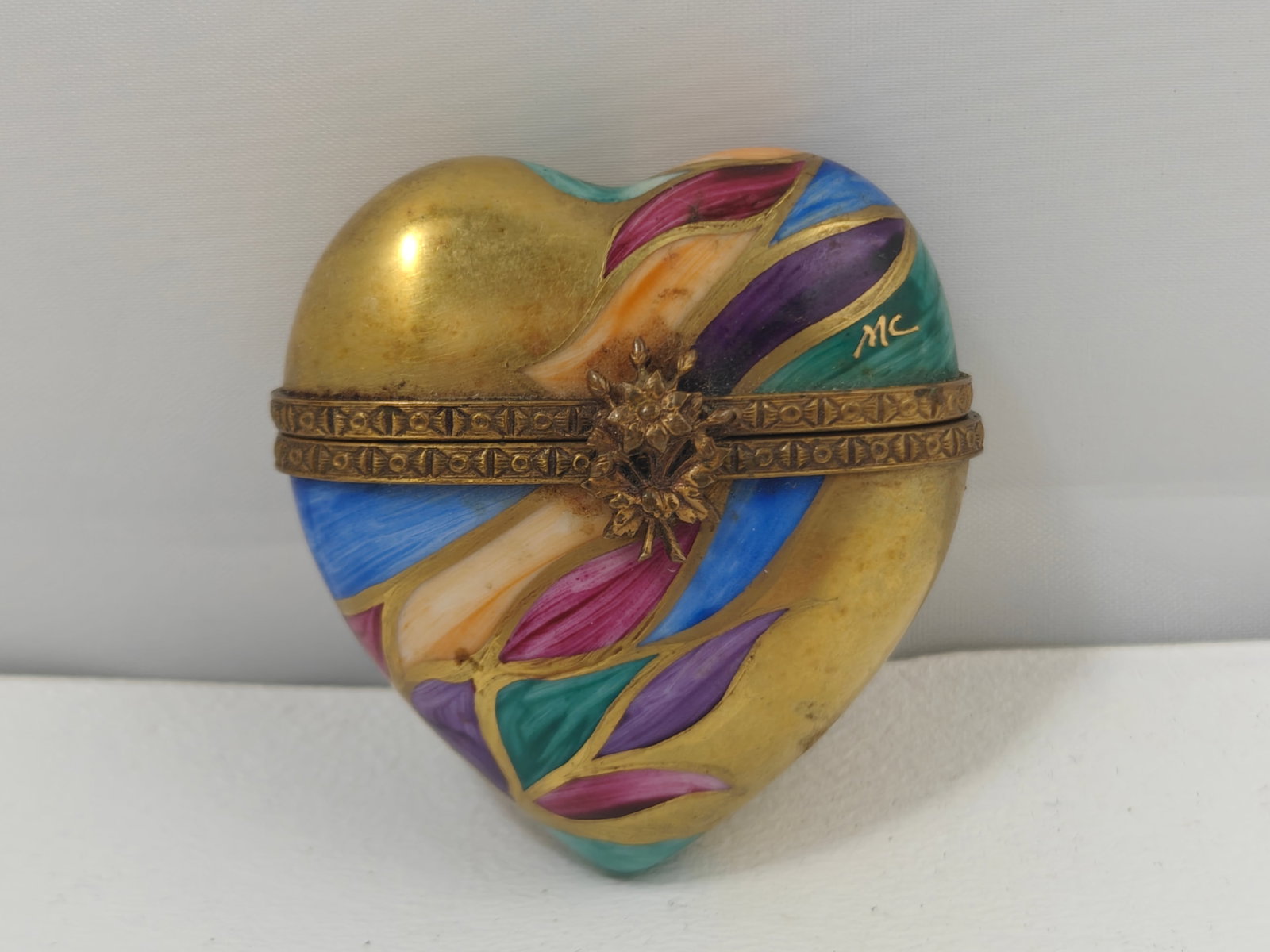 Rochard Limoges Hand-Painted Heart Porcelain Trinket Box: Hand-painted Rochard Limoges porcelain heart-shaped trinket box featuring a colorful leaf motif accented with gilt decoration and mounted in a decorative brass-tone hinged frame with floral clasp. The