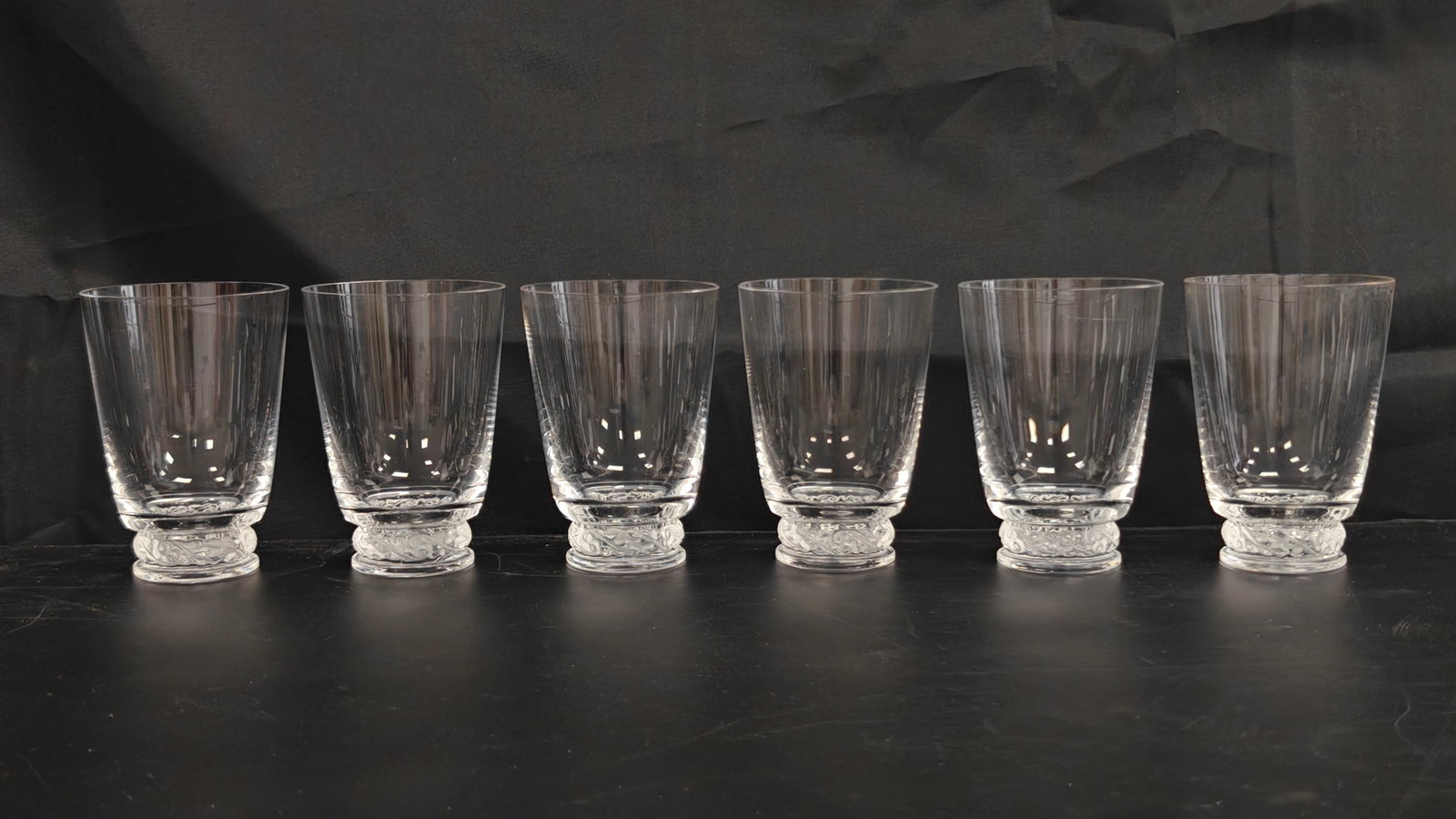 Set of 6 Lalique Saint-Hubert Crystal Tumblers: Set of six Lalique France Saint-Hubert clear crystal tumblers, each featuring the pattern's signature frosted scrolling leaf motif encircling the heavy molded foot. Acid-etched "Lalique France" signat