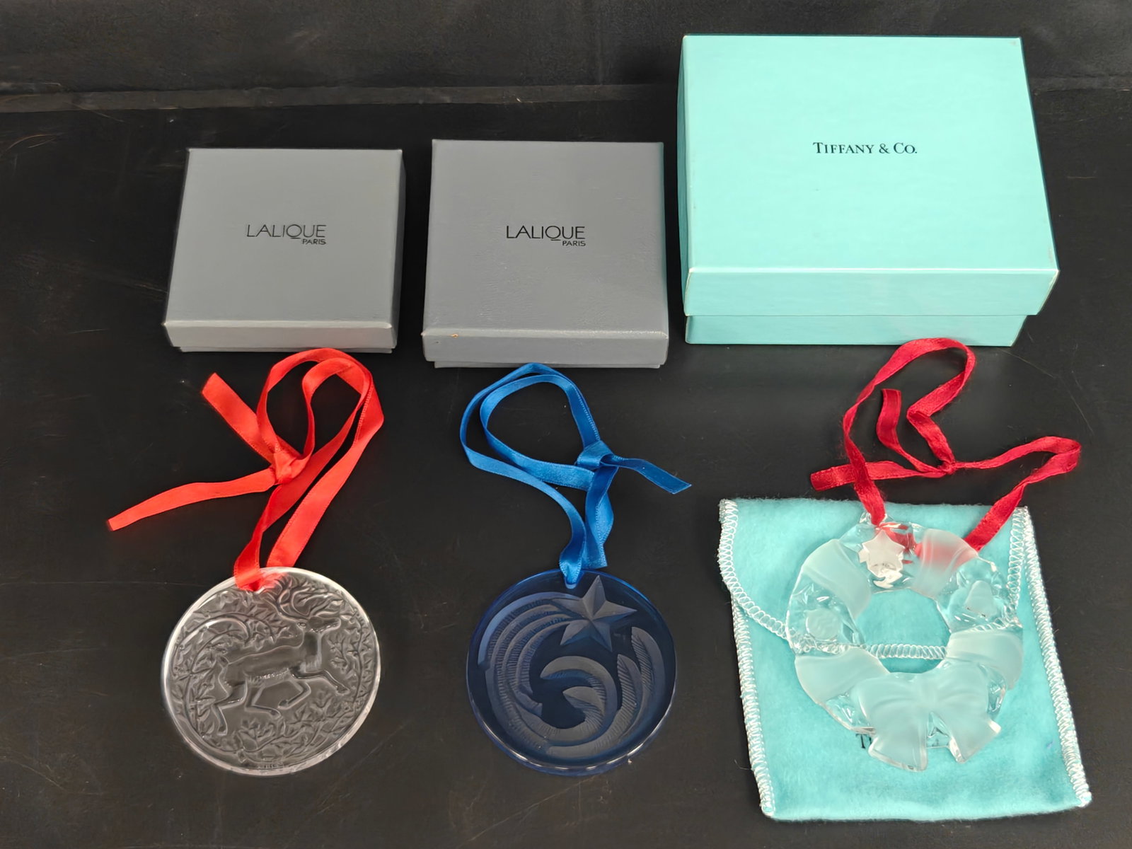 Three Designer Crystal Christmas Ornaments: Lalique & Tiffany & Co.: Collection of three designer crystal Christmas ornaments comprising a Lalique frosted crystal reindeer ornament, signed and dated 1997; a cobalt blue Lalique "Noël" comet ornament, signed and dated 2