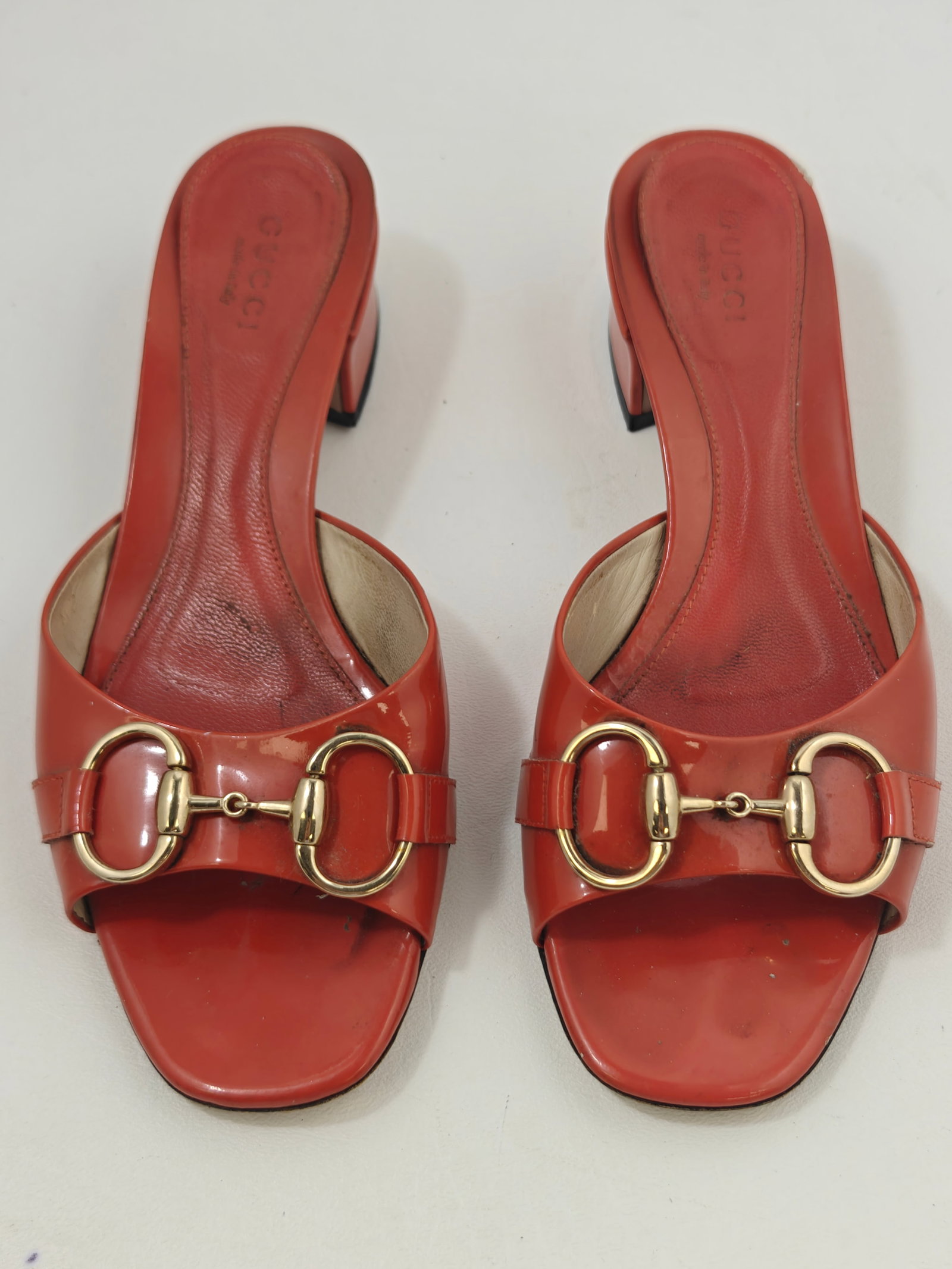 Authentic Gucci Patent Leather Horsebit Open-Toe Mule Sandals, Size 5B: Authentic Gucci open-toe mule sandals crafted in coral red patent leather with signature gold-tone horsebit hardware and low block heels. Made in Italy and marked size 5B. Features leather lining, lea