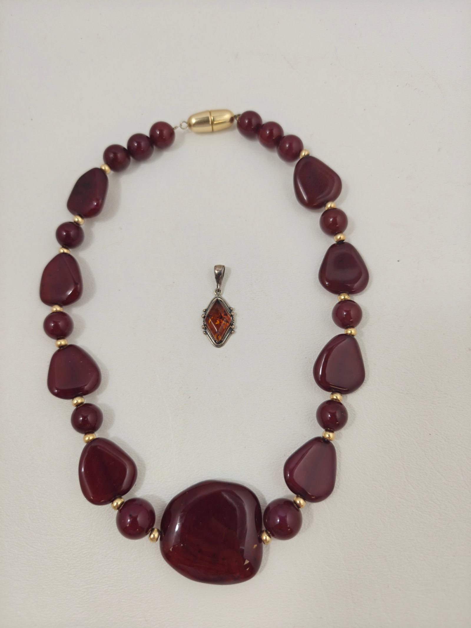 Vintage Sterling Silver Amber Pendant with Chunky Faux Amber Resin Bead Necklace: Vintage jewelry grouping including a sterling silver pendant set with a faceted cognac-colored amber stone in an ornate bezel, accompanied by a chunky necklace composed of organic-shaped reddish-brown