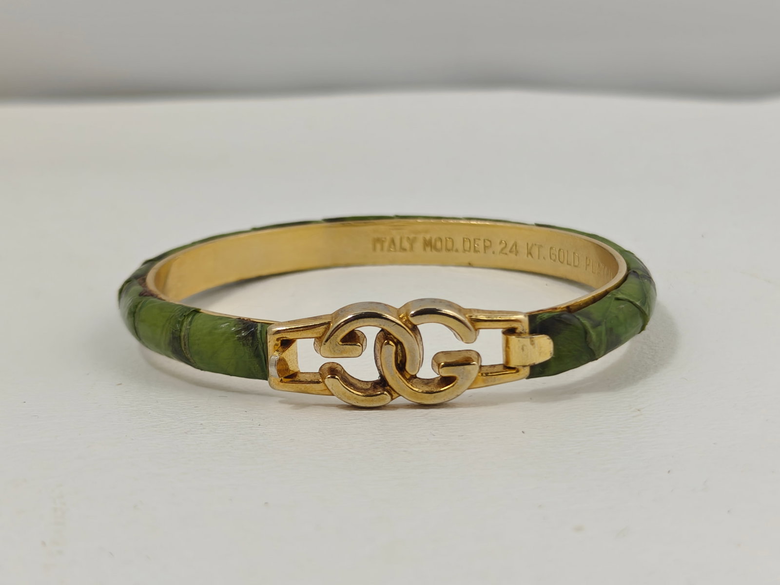 Vintage Gucci Green Snakeskin & 24K Gold-Plated GG Hinged Bangle Bracelet: Vintage Gucci hinged bangle bracelet featuring green snakeskin-covered exterior with polished 24K gold-plated hardware and signature interlocking GG clasp. Interior stamped "ITALY MOD. DEP. 24 KT. GOL