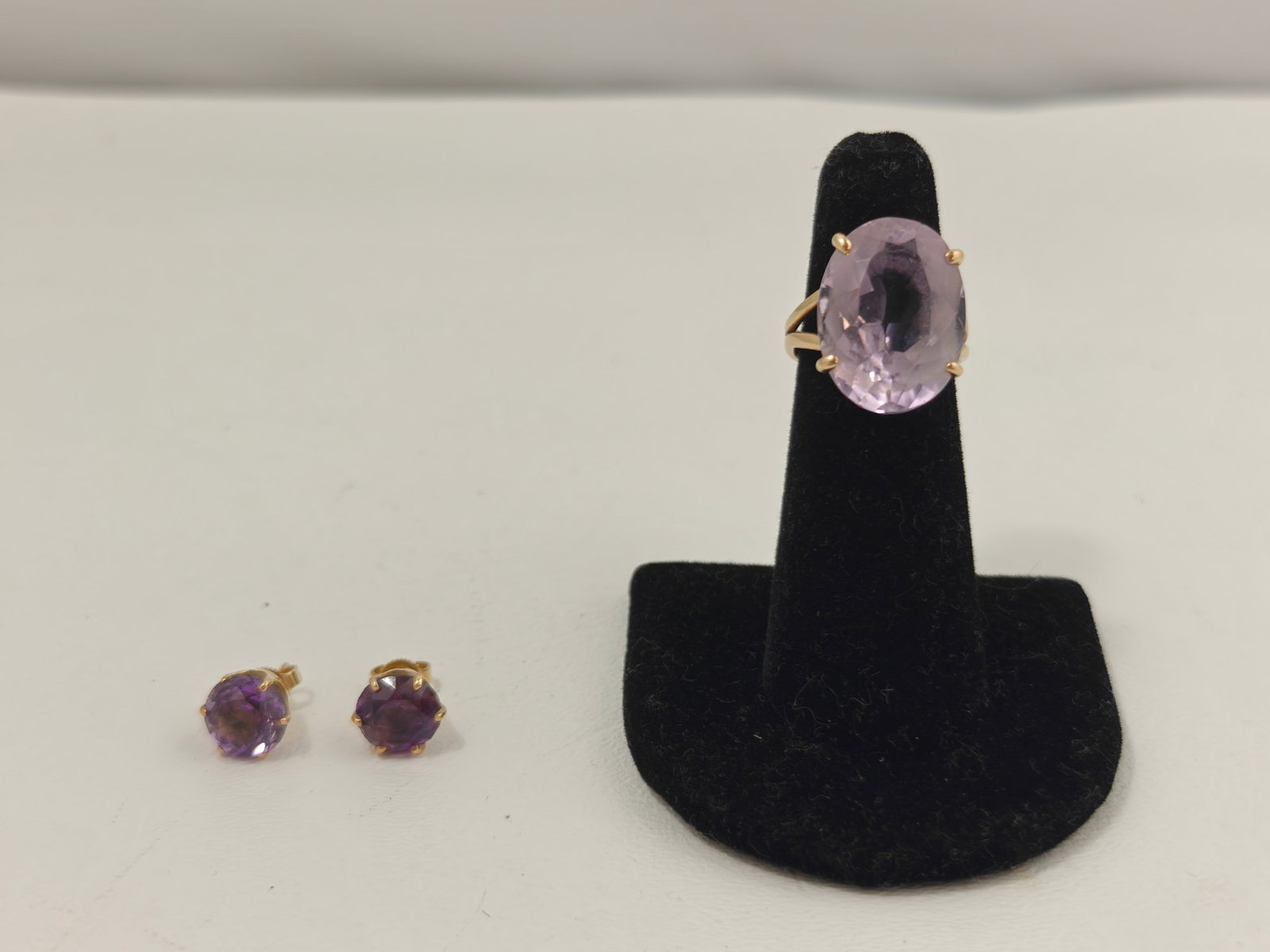 14K Gold Amethyst Stud Earrings & Lavender Stone Ring: Group including a pair of round faceted amethyst stud earrings in 14K yellow gold four-prong settings, with 14K-marked friction backs. The earrings measure approximately 6.3 mm in diameter. Also inclu