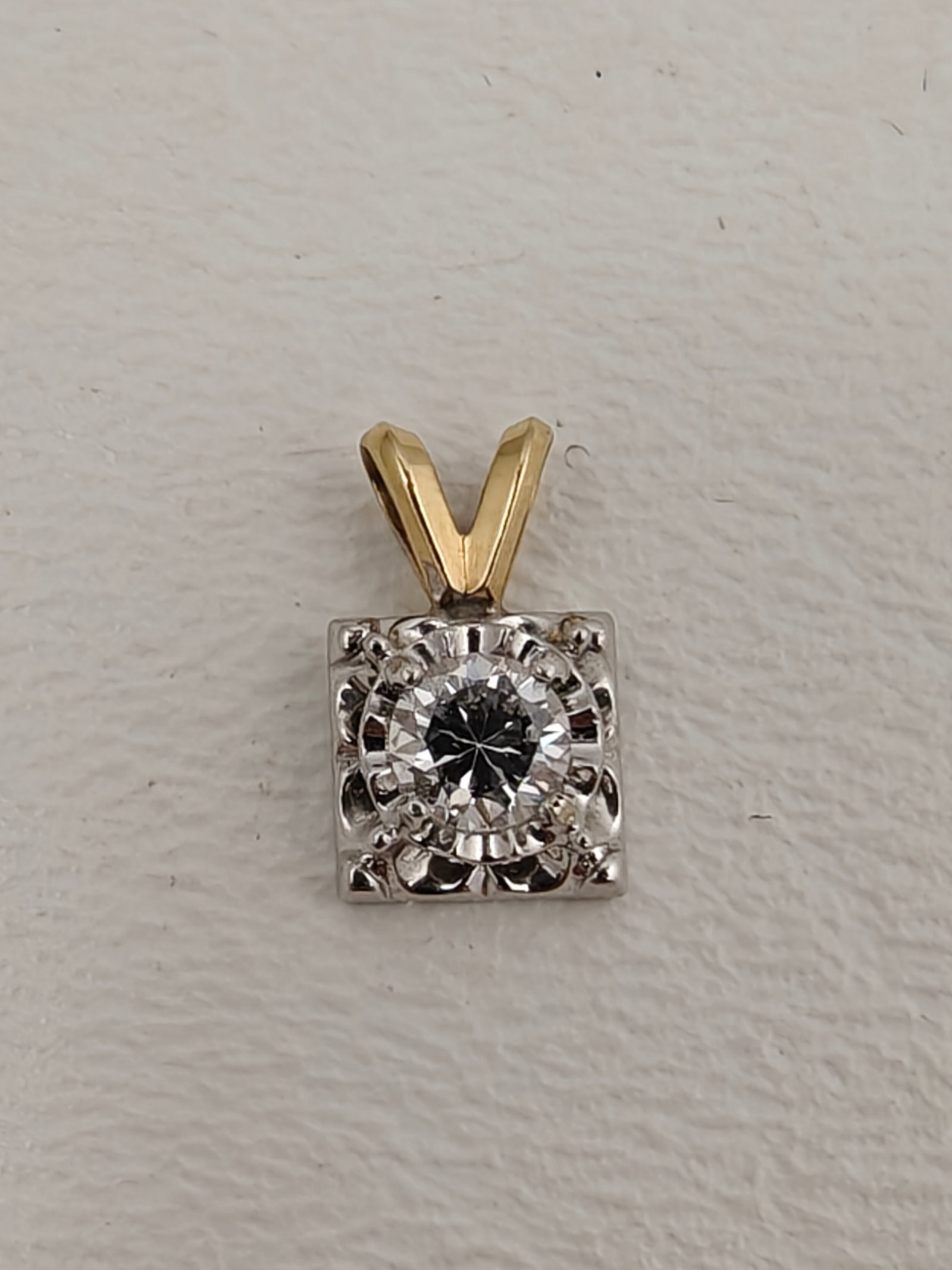 14K Gold Diamond Solitaire Pendant: Classic solitaire pendant featuring a round brilliant-cut diamond mounted in a white gold square basket with decorative openwork, suspended from a yellow gold tapered bail. The two-tone design offers 