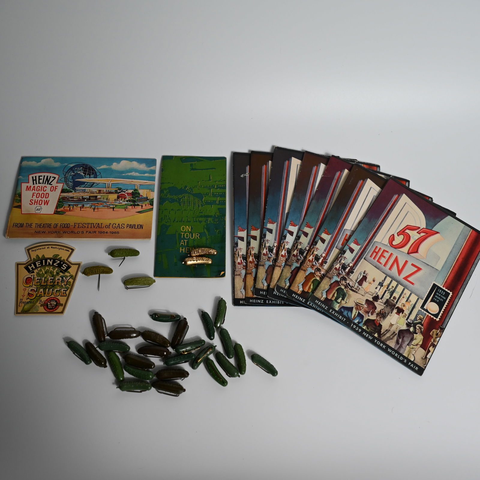 Collection of Heinz Memorabilia incl. 20+ Pickle Pins: (1) Heinz Exhibit - 1939 New York World's Fair, small booklet about 7.25 x 5 inches. Opens about 14 x 20 inches showing Heinz Exhibit. Lot of 7. (2) Heinz Magic of Food Show, From the Theatre of Food