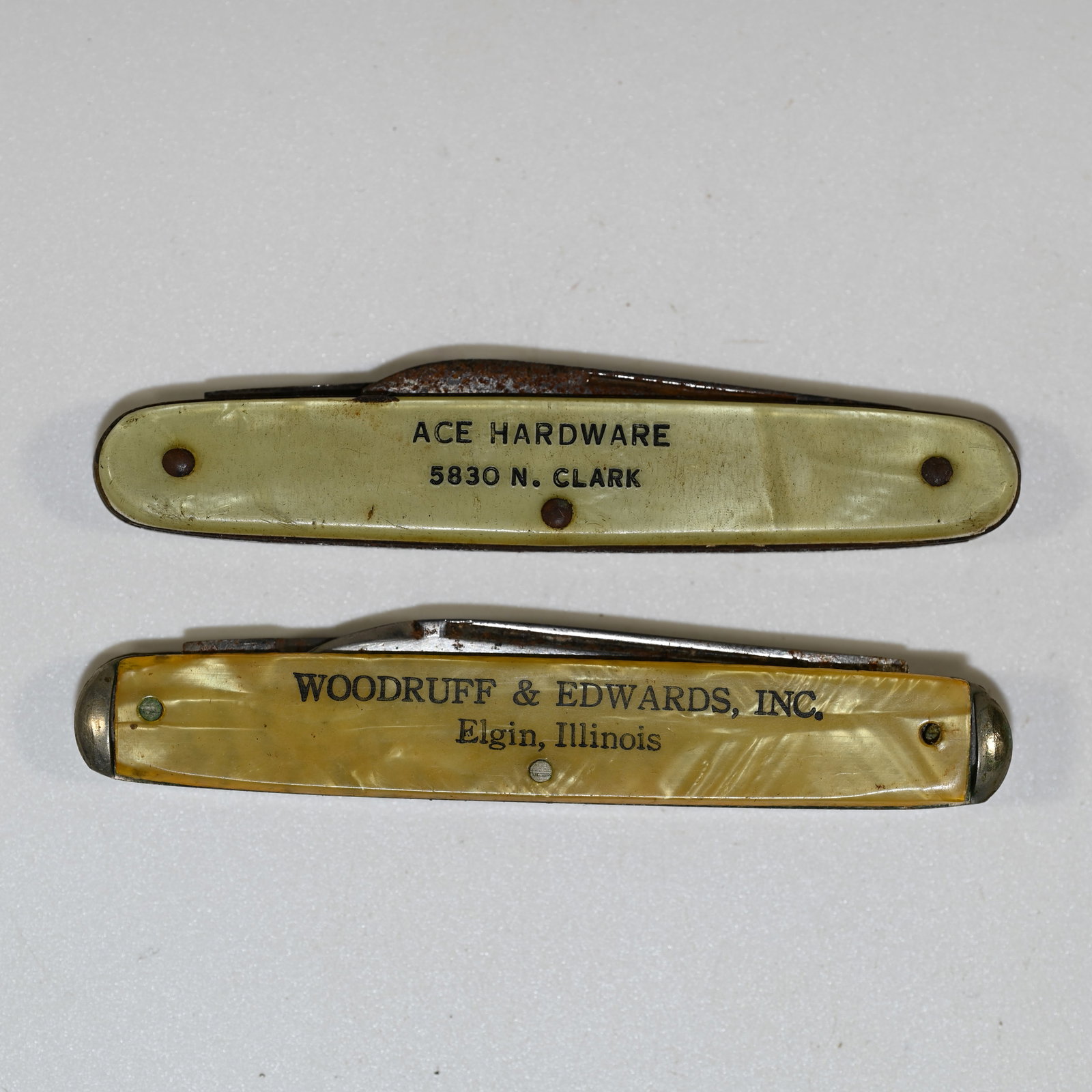 Lot of 2 Advertising Pocket Knives, one Kutmaster: 1 - Ace Hardware, 3 inches long with 2 blades. Large blade marked Autopoint Chicago. 2 - Woodruff & Edwards 2-blade knife, 3 1/4 inches long, longest blade is about 2 inches long and is marked