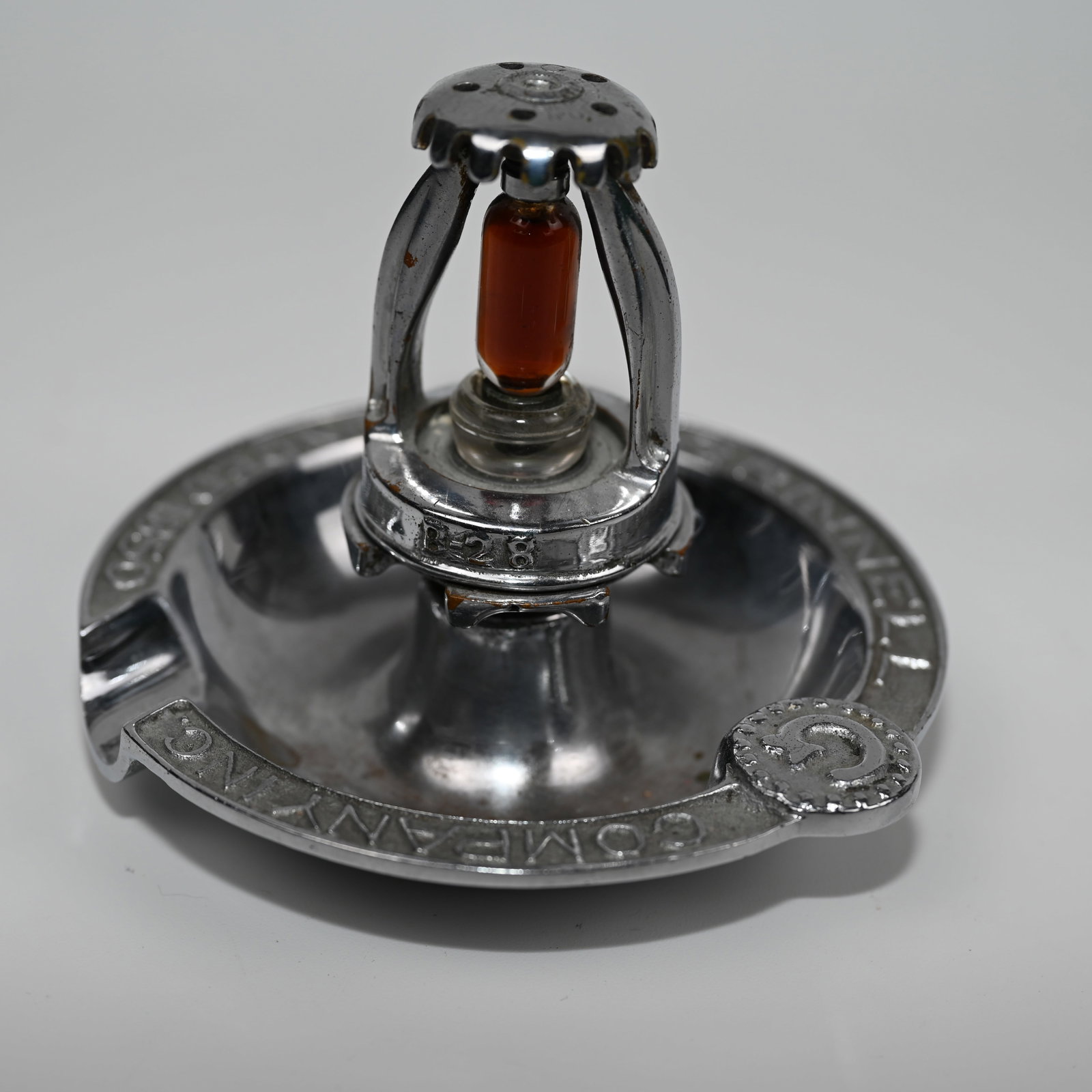 Grinnell Company Fire Sprinkler Ashtray: An ashtray marked Grinnell Company Inc Founded 1850 featuring a Grinnell fire sprinkler that is marked 1350 on one side and B-28 on the other, likely a model number. About 3 1/2 H x 4 3/8 W x 4 3/8 D 