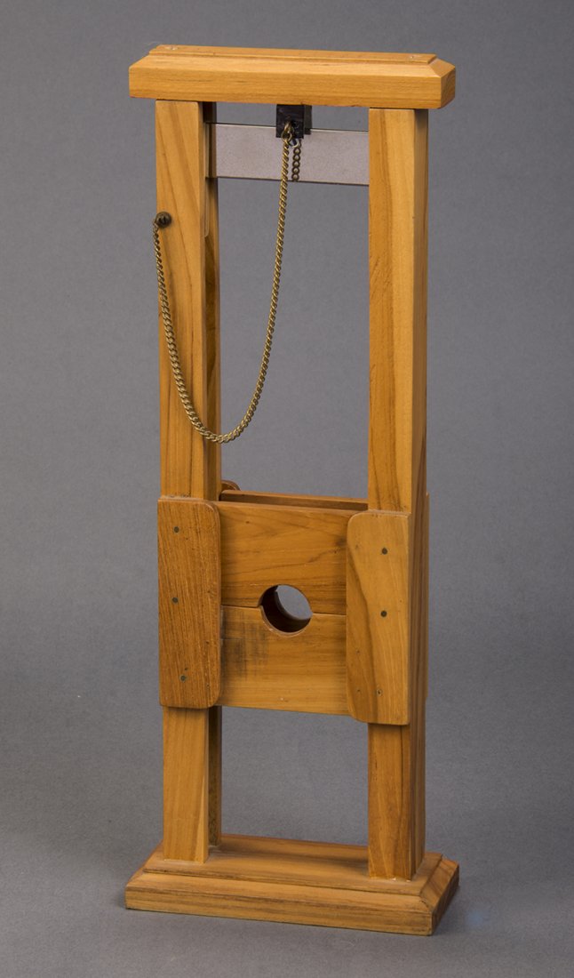 Mini Guillotine – MAK Magic: MAK Magic. Miniature hardwood guillotine stands 13” tall. Spectator is coerced to put their finger in the stocks. The blade falls, mysteriously penetrating the finger. Condition: Excellent.