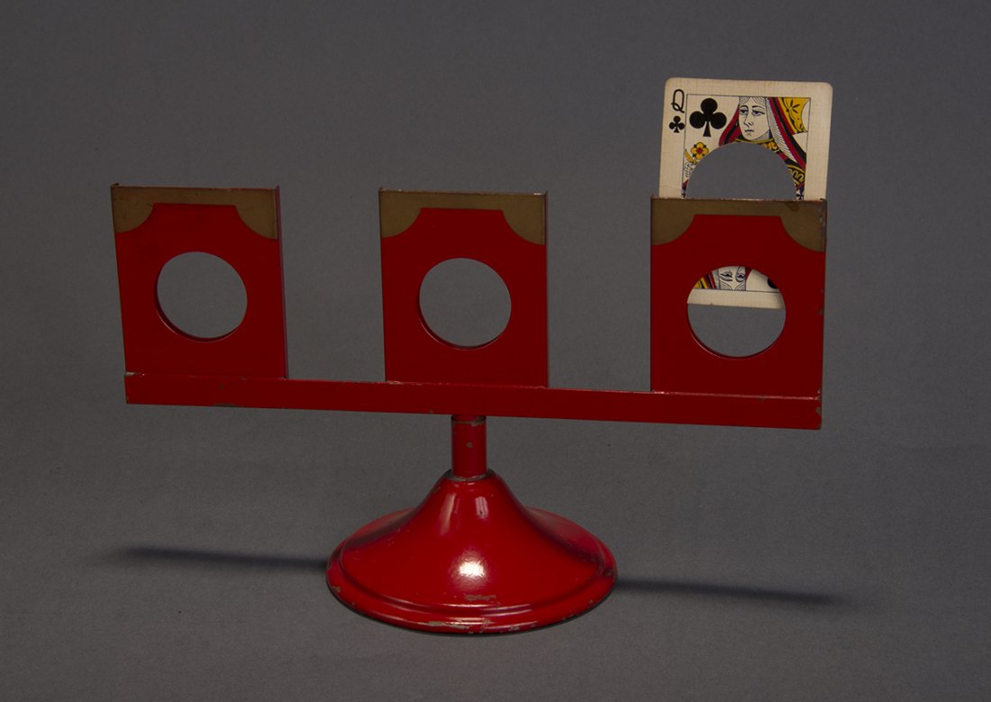 Cherchez La Femme (Standard sized) – Petrie & Lewis: Lacquered in red and gold, this metal stand is P&L’s version of Find the Lady. The cards are mixed and the spectator can never find the Queen. Al Baker (1874-1951) is credited with inventing this ve