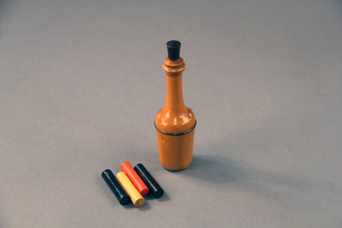 Magic Bottle and Mystic Colors - Bland: Circa 1890. A finely turned 4” tall wood vase is shown, along with four colored rods. Out of view of the magician, a member of the audience chooses one of the rods, places it into the neck of the bo