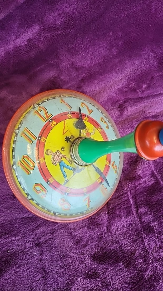 Tin Litho Clock Face Spinning Top Toy With Green Handle And Red Base: Works 7 x 9. 5 x 7 1. 0 lb Low Estimate: 10.00 High Estimate: 45.00