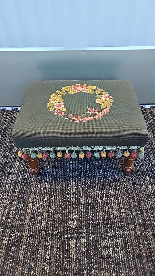 Green Needlepoint Floral Upholstered Footstool Ottoman With Pom-pom Fringe Wooden Legs: Needs some spot cleaning 18 x 10 x 16 8 lb Low Estimate: 25.00 High Estimate: 85.00