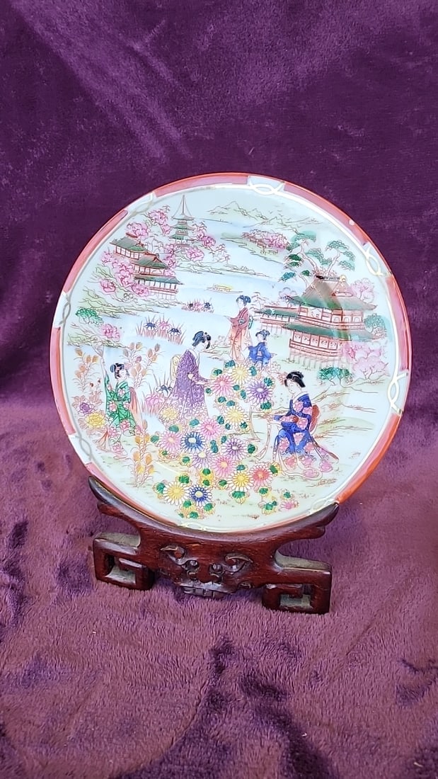 Japanese Porcelain Decorative Plate With Geisha Garden Scene And Wooden Display Stand: 8. 5x11x4 1lb Low Estimate: 15.00 High Estimate: 45.00