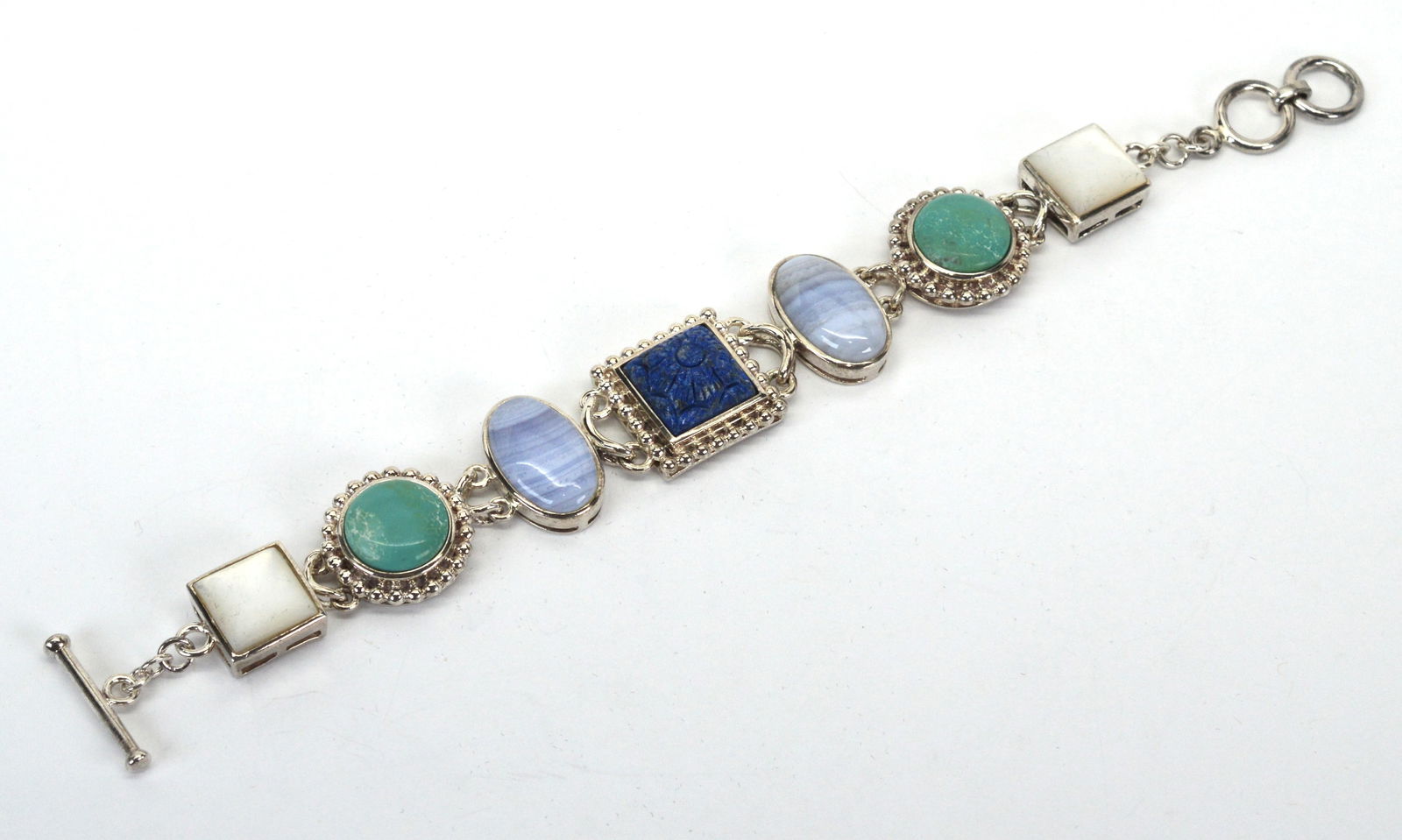 Whitney Kelly Sterling Silver Multi Gemstone Station Bracelet: Whitney Kelly Sterling Silver Multi Gemstone Station Bracelet w colorful Carved Lapis Lazuli Center Stone, Blue Agate, Turquoise and Mother of Pearl with a adjustable toggle closure 7.5 to 8". Each ge