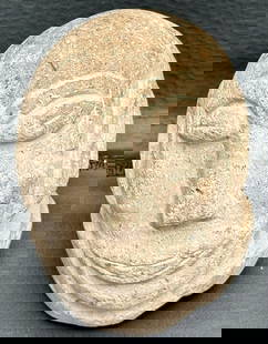 Primitive Stone Head Sculpture Carving: Primitive-style carved stone sculpture representing a stylized human head. Made of natural stone with a textured and aged surface. The facial features are deeply engraved, including almond-shaped eyes