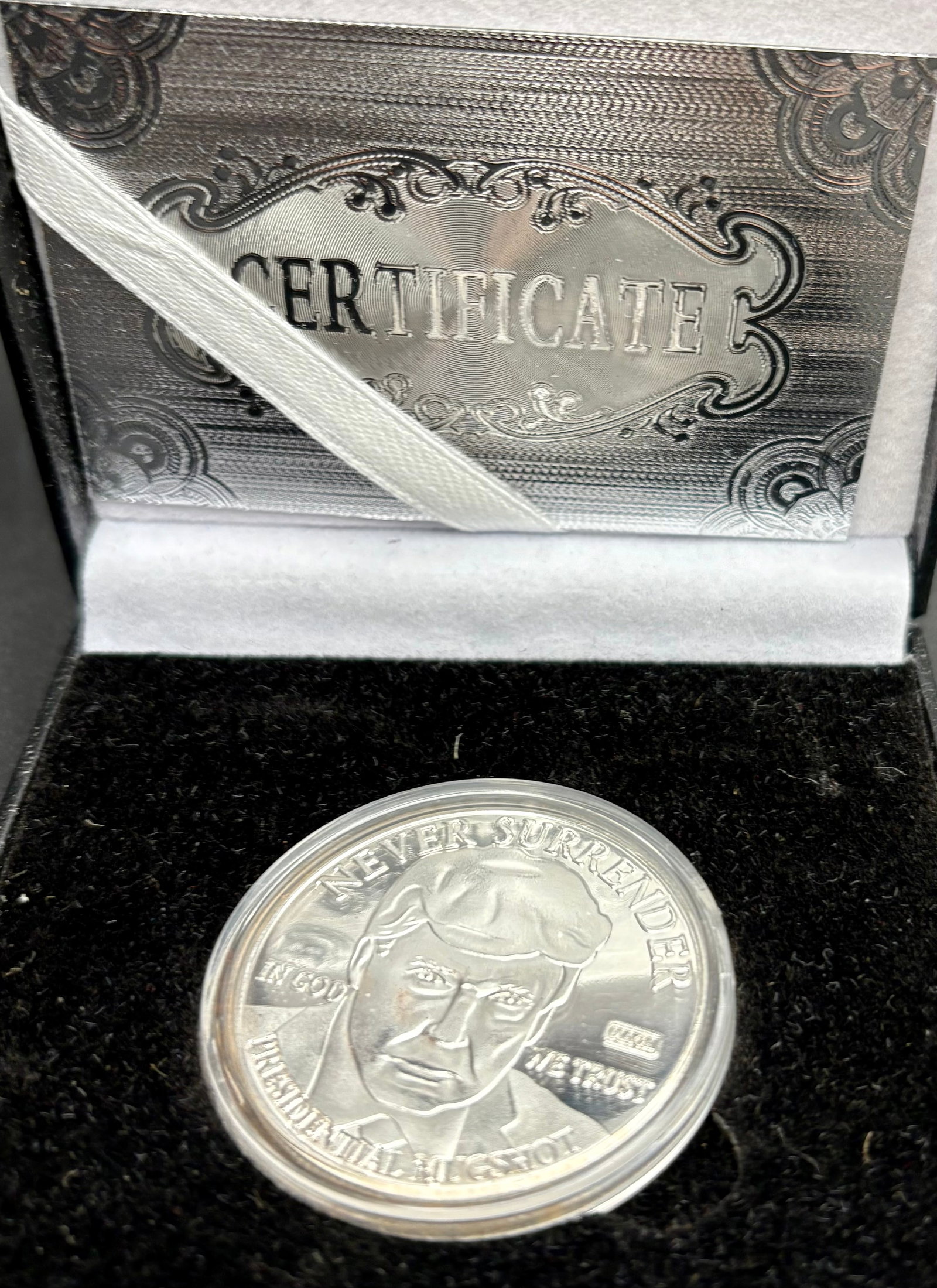 Donald Trump Silver-Tone Commemorative Coin with Box and Certificate: Striking Donald Trump commemorative coin in a silver-tone finish, featuring the slogan “NEVER SURRENDER” and a portrait of Trump. The coin is marked with “IN GOD WE TRUST” and “PRESI