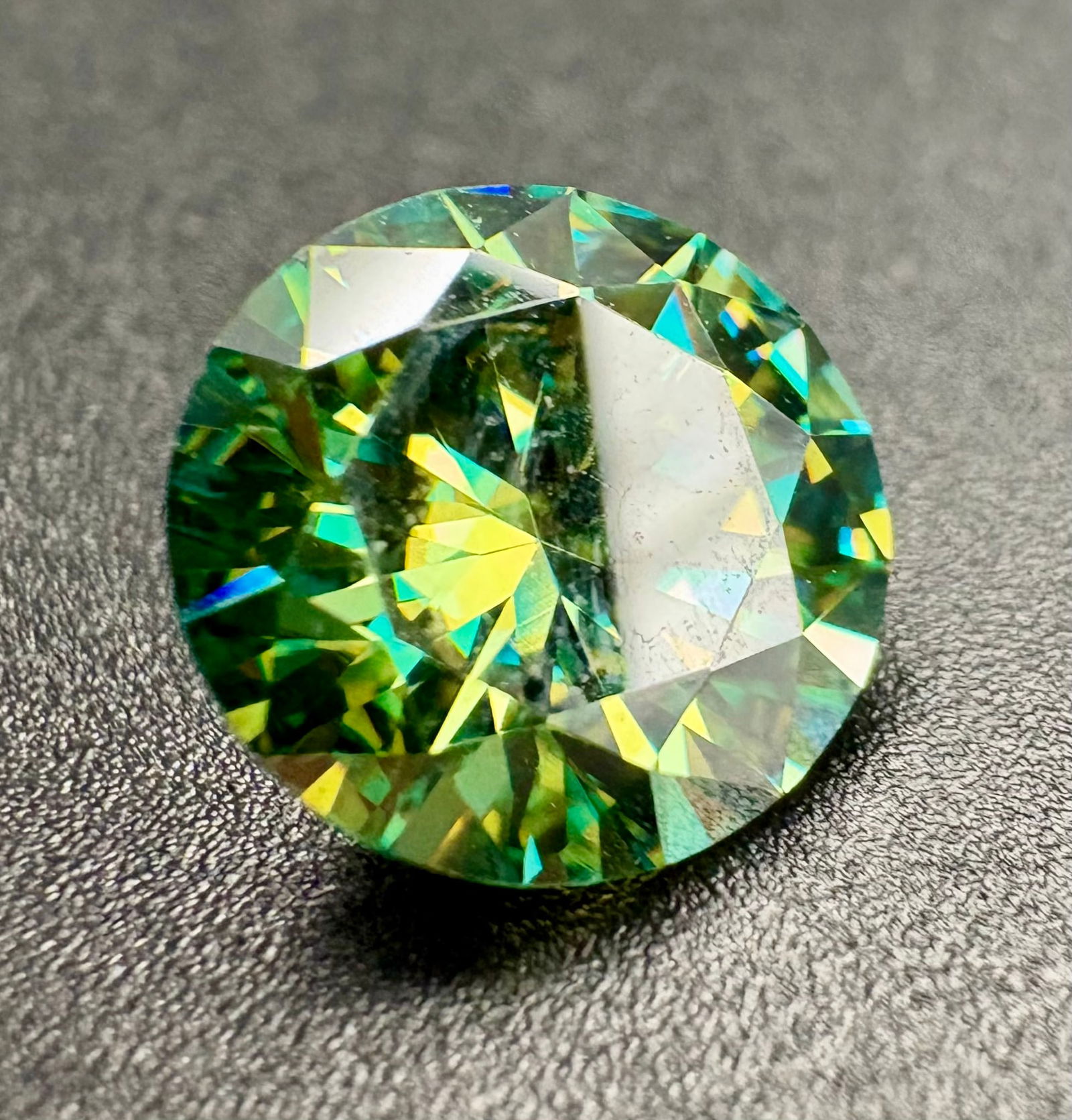 Stunning round brilliant Moissanite with a vivid green hue: Stunning round brilliant Moissanite with a vivid green hue and exceptional sparkle. The gem features excellent faceting and high clarity, making it ideal for standout custom jewelry. Estimated weight: