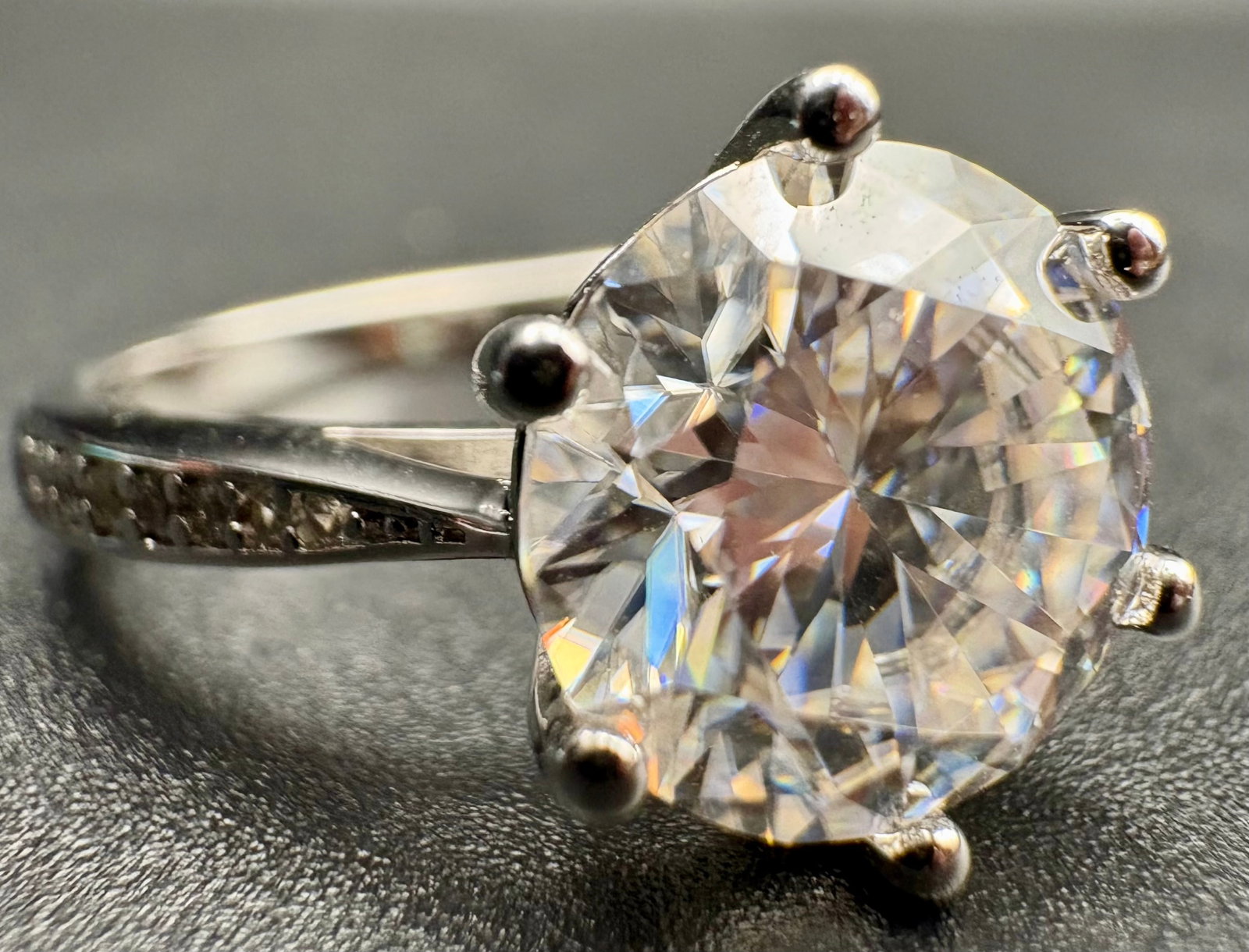 Moissanite Engagement Ring - Round Brilliant Cut: Moissanite Engagement Ring - Round Brilliant CutStunning engagement ring featuring a large round brilliant-cut Moissanite stone, securely held by six prongs. The band is accented with small stones alo