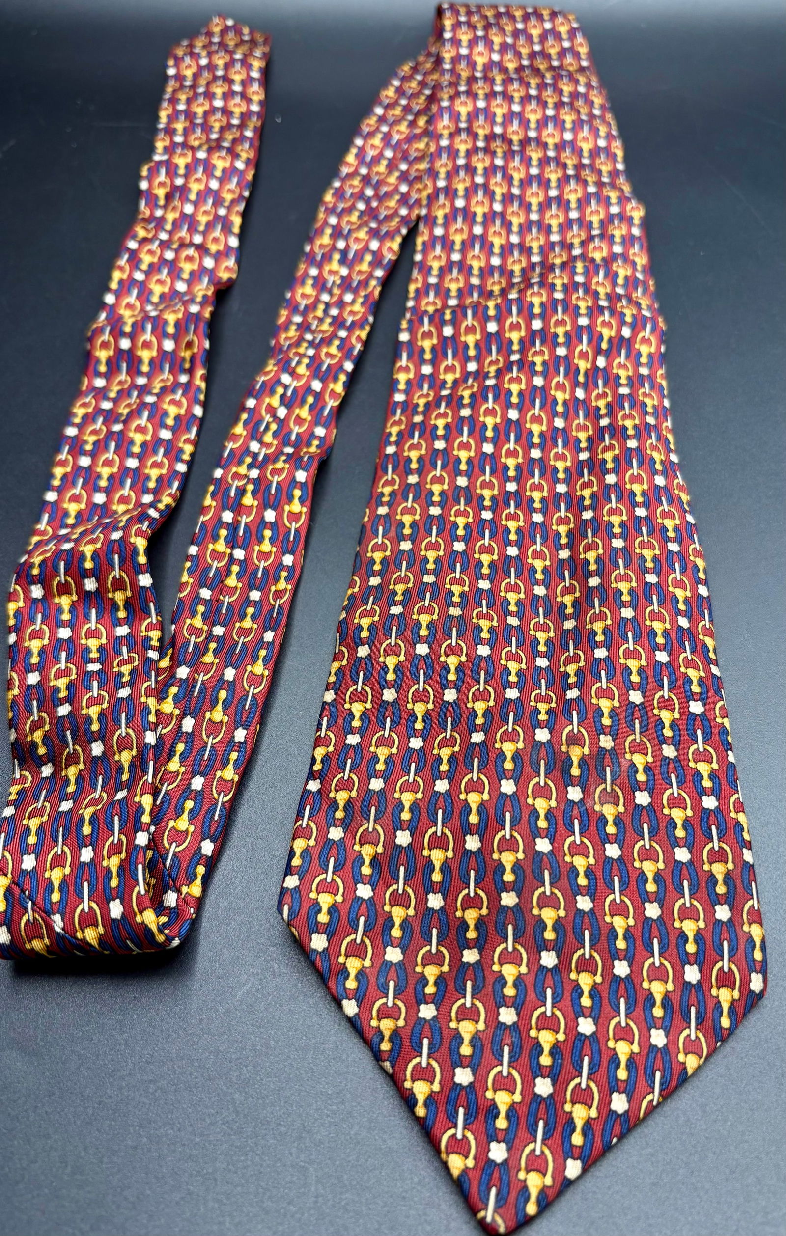 Luxury tie by Burberry,: Luxury tie by Burberry, made of pure silk, featuring a bold pattern of yellow, blue, and white links over a burgundy background. A refined and elegant accessory, perfect for formal occasions or collec
