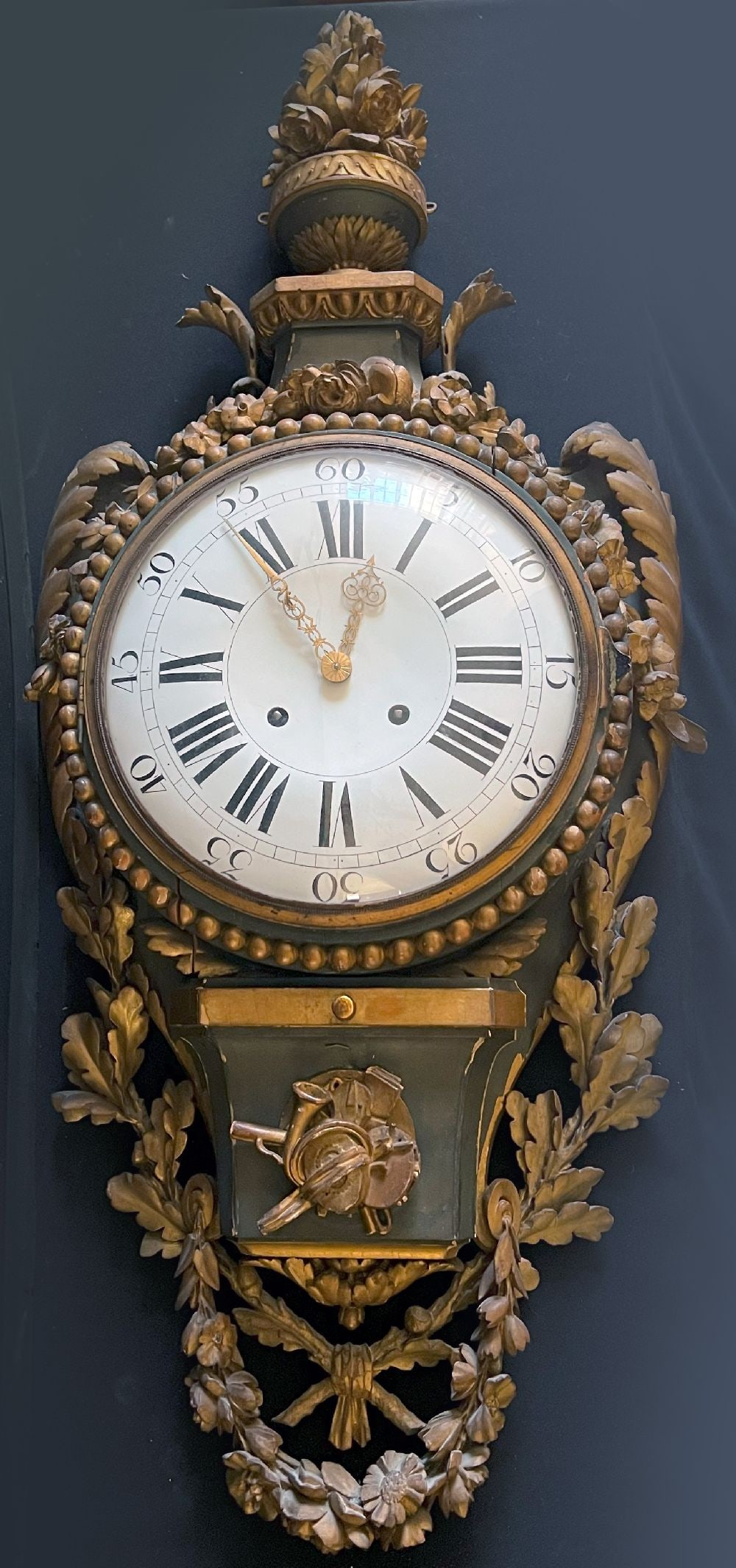 Large wall clock: Large wall clock, circa 1800, wood, carved with oak leaves and floral garlands, topped with an urn with flowers, coloured frame, dial with Roman numerals, clock runs on (movement probably from the sec