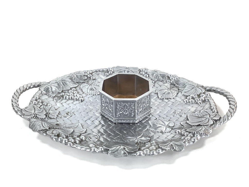 Lenox Metal Serving Tray & Wine Bottle Coaster: Holloware wine bottle coaster with cork lining, 5 1/4"W, surface wear and residue on the bottom Serving tray with handles, grape vine leave weave pattern, 22 1/2"W, overall good condition, minor wear.