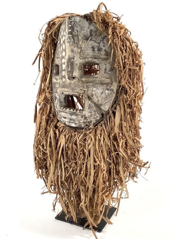 Ituri Style Mask From The DRC: 8"H x 7"W not including the raffia, comes with metal stand. Provenance: Collected by Sophia and Roy Sieber.