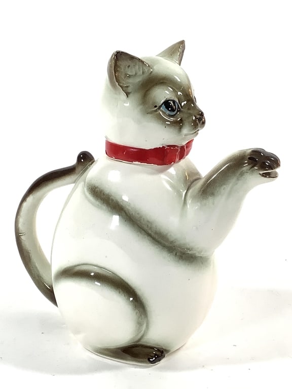 Siamese Cat Teapot 1950-60s Japanese Kasuga Ware: 8 1/2"H. Clasped paws form the spout, tail forms the handle. Loss and repair to glaze on the left ear, crazing. Unmarked. Provenance: Collection of William and Diane Itter.