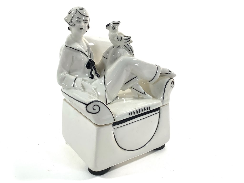 German Figural Art Deco Trinket or Powder Box: 5 1/2"H. Box in the form of an armchair, woman with bobbed hair in lounging attire and parrot seated on lid. Model numbers stamped on lid and base, orange stamp mark Germany with number 18 on unglazed