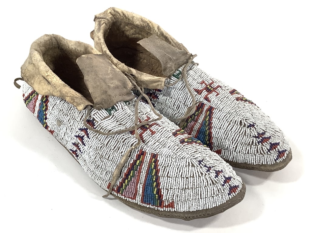 Fully Beaded Polychrome Hide Moccasins: 11"L x 3 1/2"W. Expected wear to hide and soles. Beadwork largely intact, with colorful geometric patterns. Provenance: Collection of William and Diane Itter.